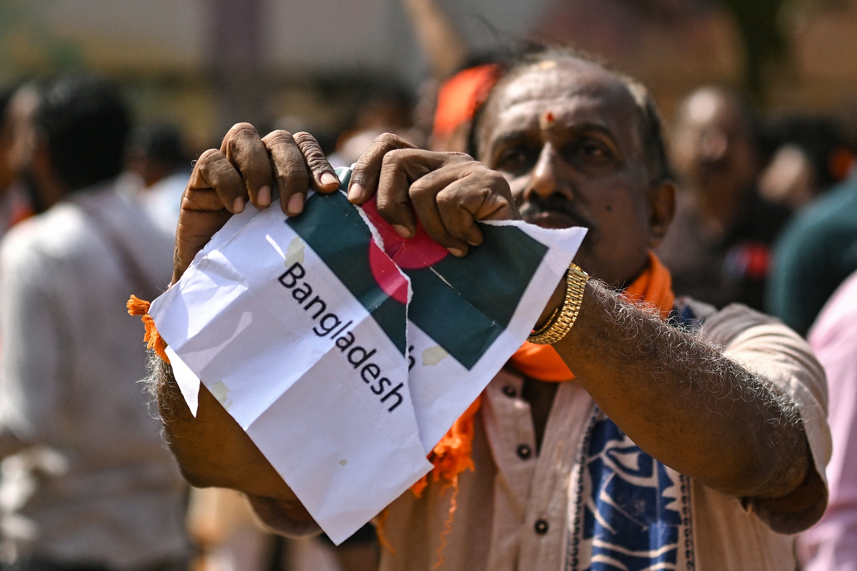 A Hindu Rashtra Coordination Committee supporter tears a paper featuring Bangladesh's national flag to protest alleged atrocities against Hindus, at the Freedom Park in Bengaluru on December 28, 2025