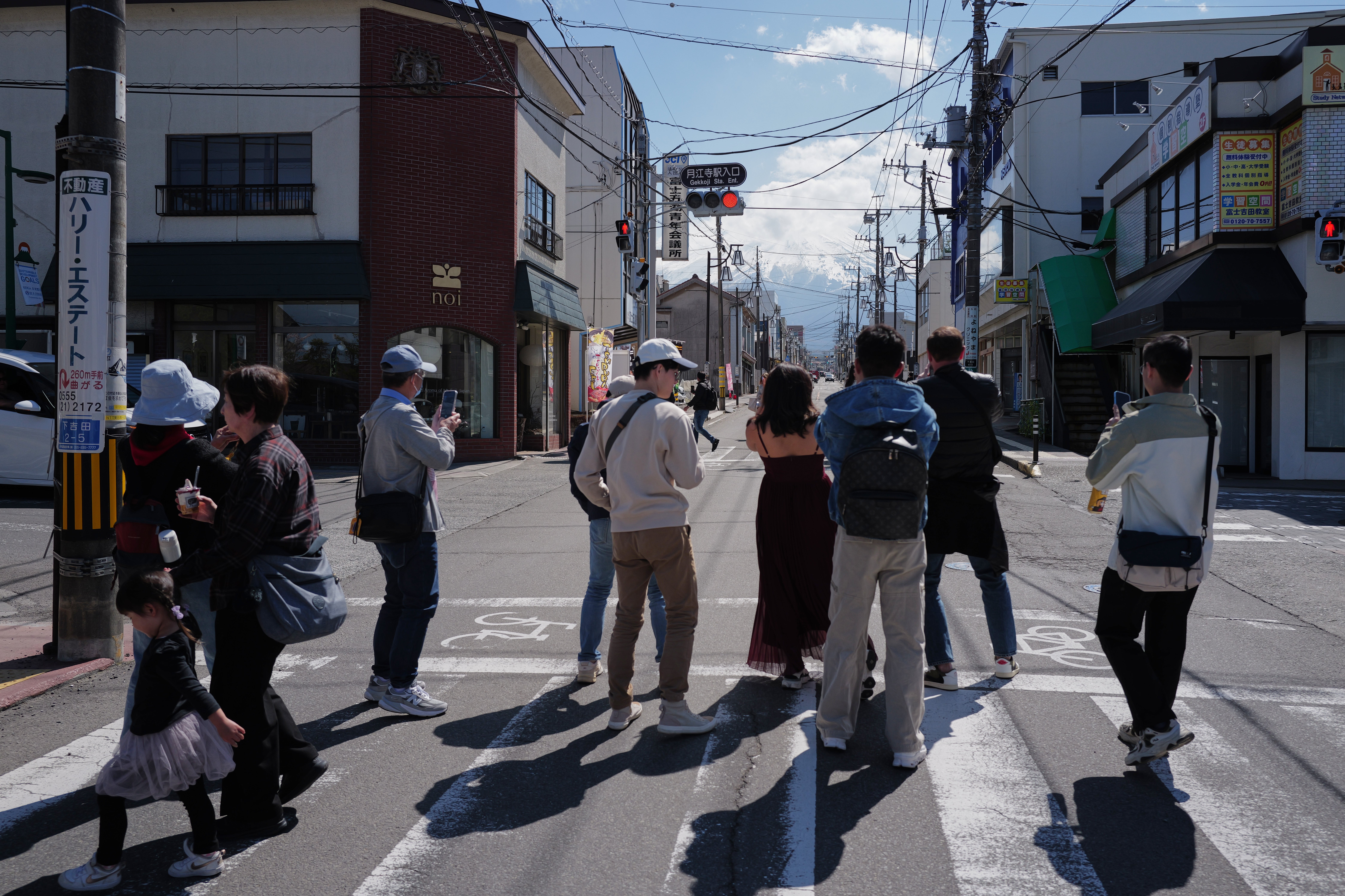 Tourists stand in the street to take photos of Mount Fuji