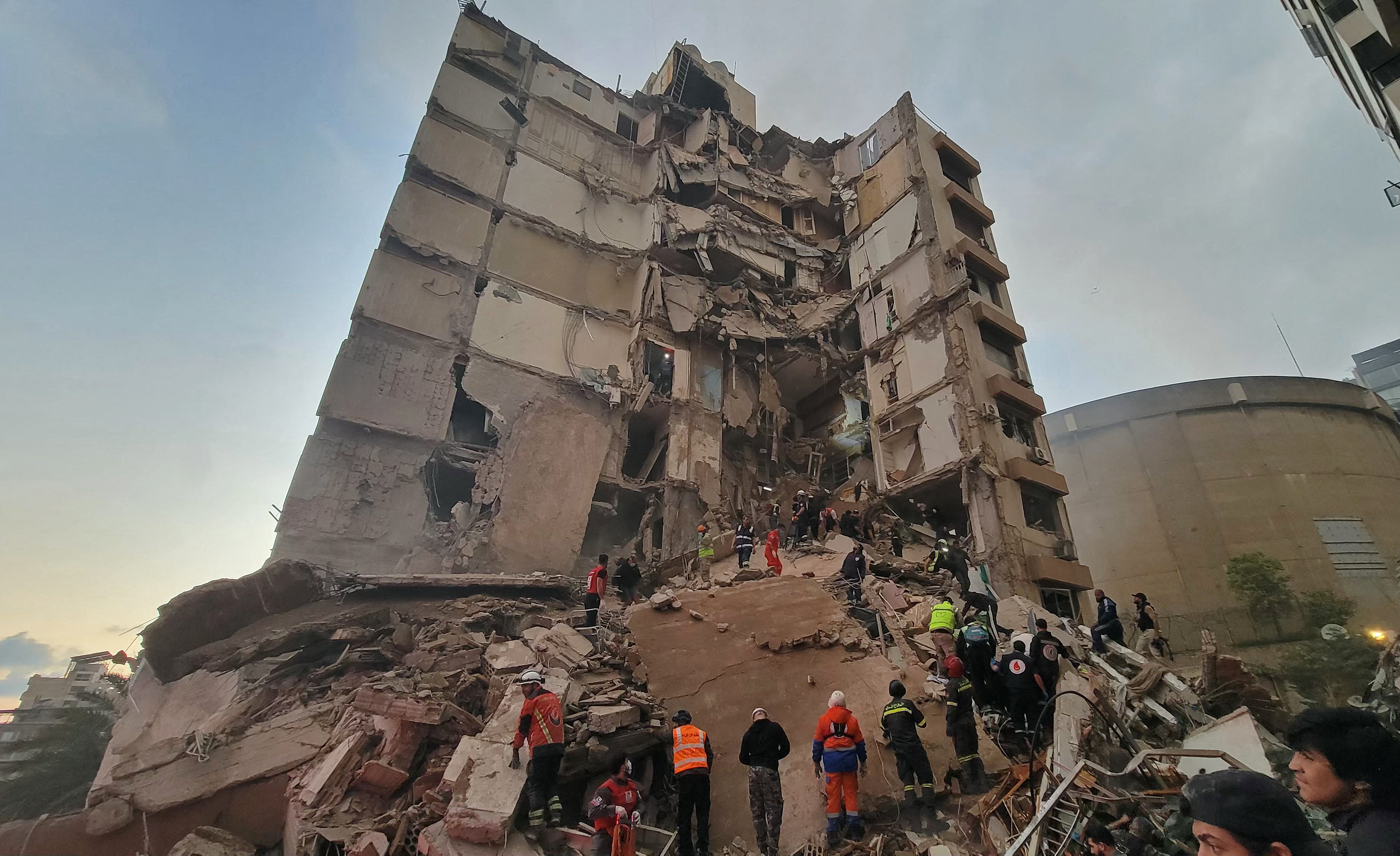 Сотрудники службы экстренного реагирования и жители собираются на месте израильского авиаудара в районе Бейрута Таллет аль-Хайят в среду.