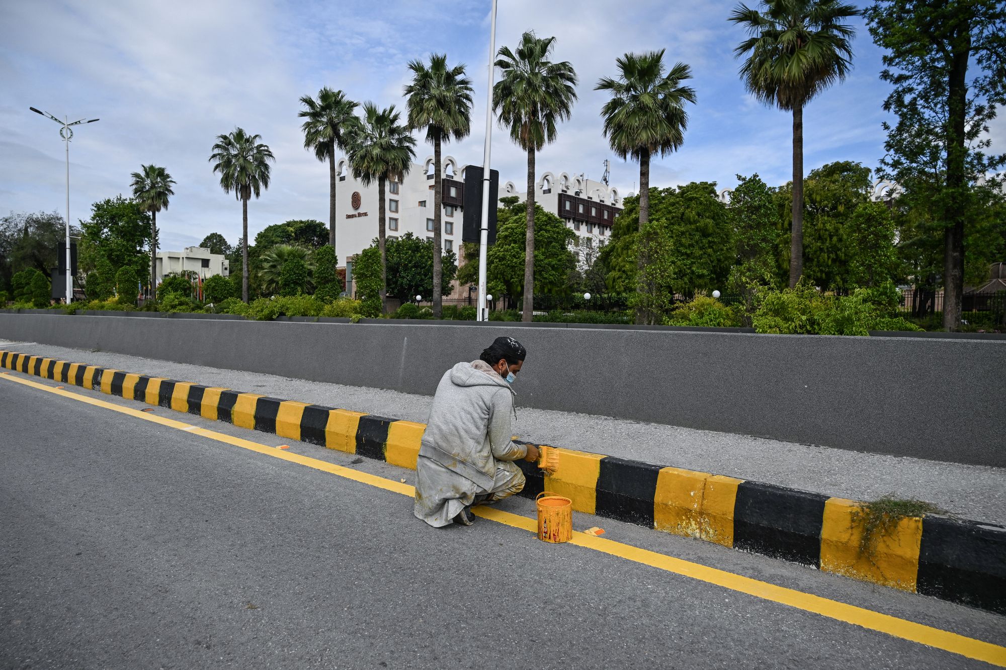 A worker paints a road separator near the Serena Hotel, the expected venue for US-Iran talks, in Islamabad