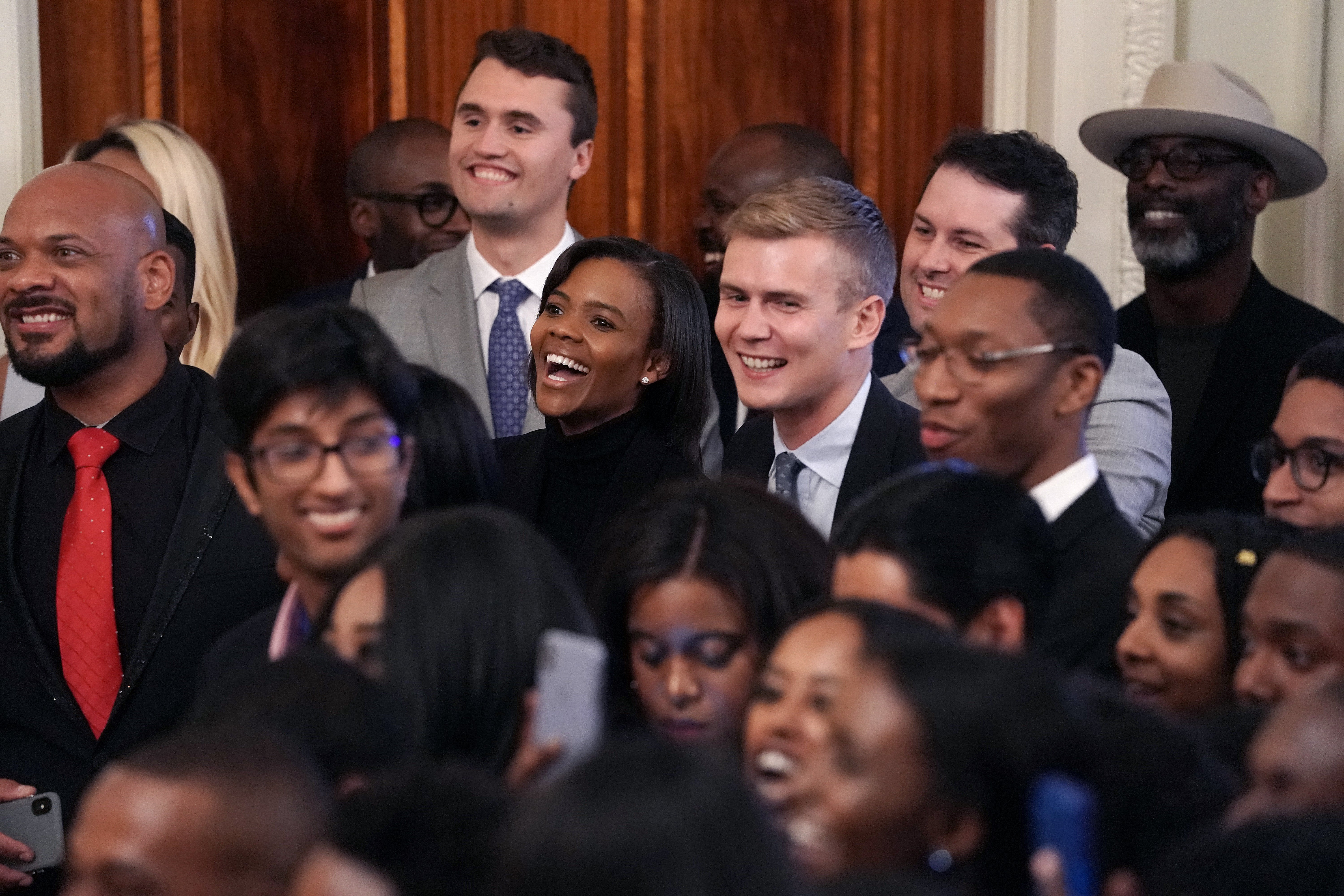 Turning Point USA founder Charlie Kirk (top), Candace Owens (C) and her husband George Farmer join other guests while listening to President Donald Trump address an event for the Young Black Leadership Summit in the East Room of the White House in 2019