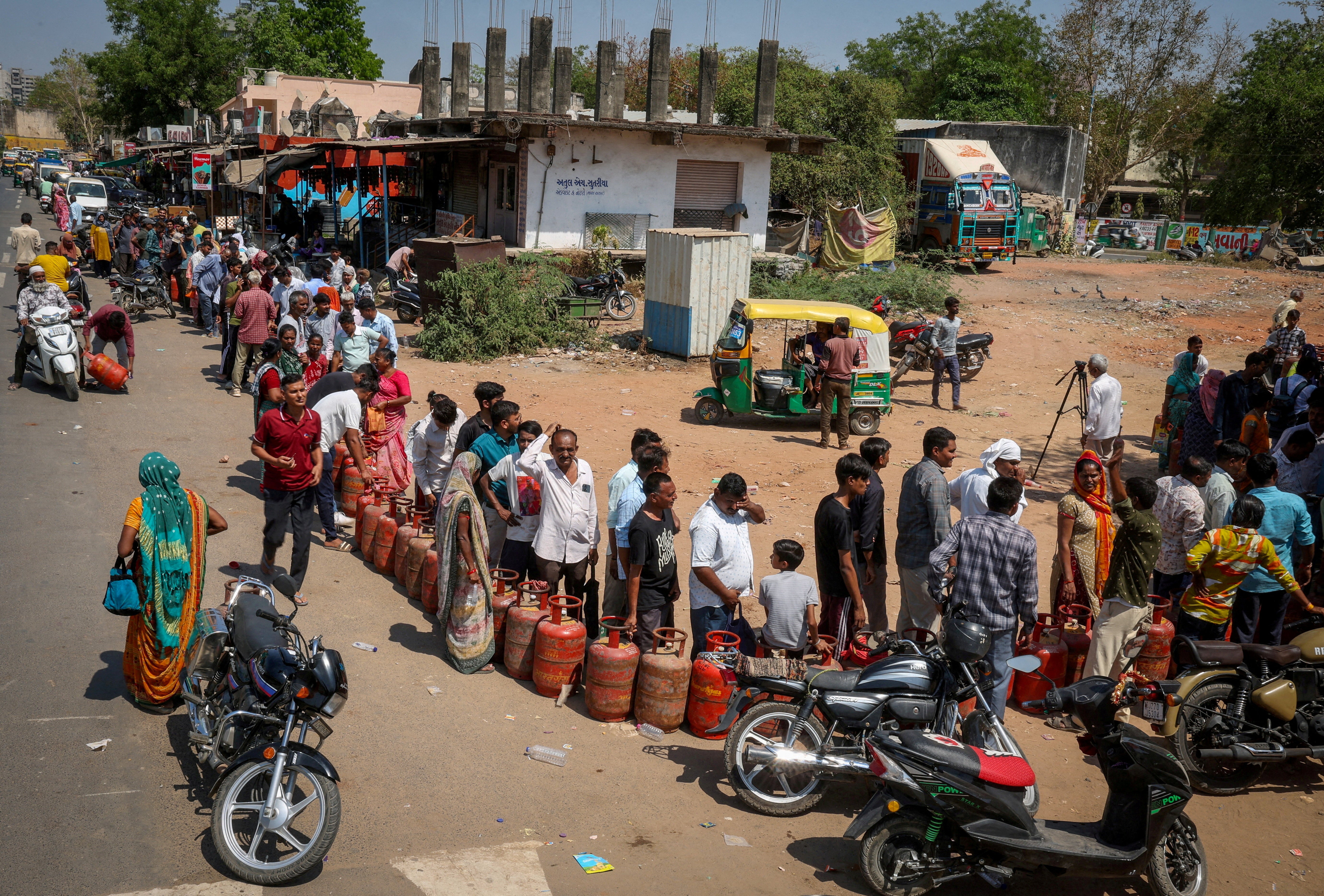 People stand in a queue to refill LPG cylinders outside a gas agency in Ahmedabad