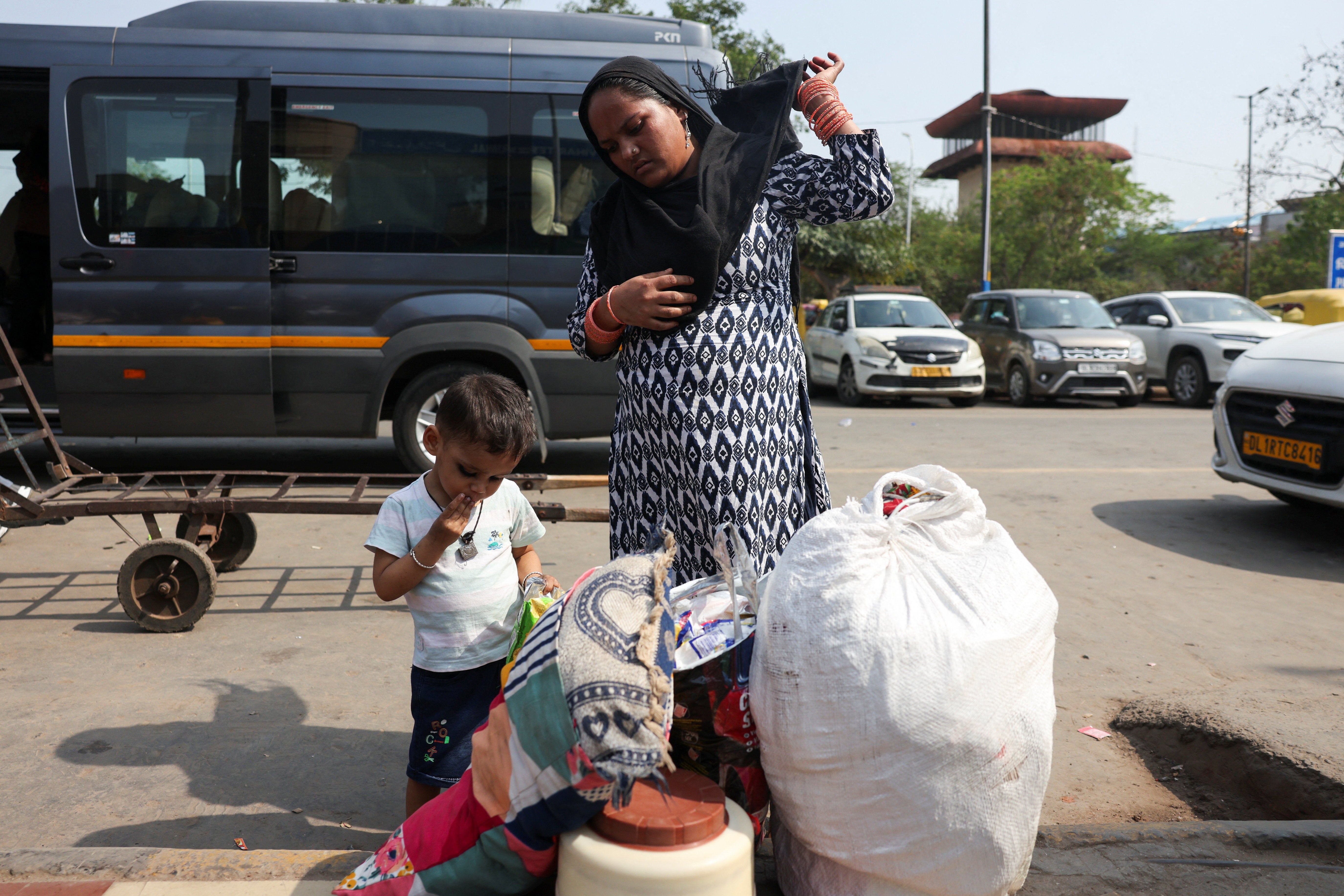 Husnara Khatun, 32, stands with her belongings outside the New Delhi railway station as she waits to travel back home to Bihar with her husband