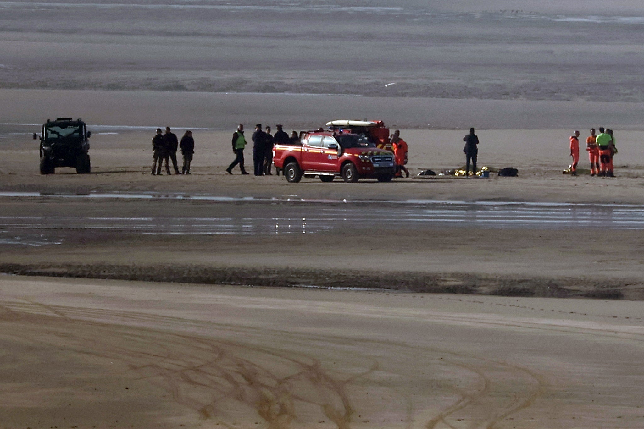 Rescue vehicles and medical units gather on the beach to treat victims after an attempt to cross the English Channel illegally turned tragic with several migrants found in cardiac arrest, in France's Pas-de-Calais northern coastal city of Equihen-Plage