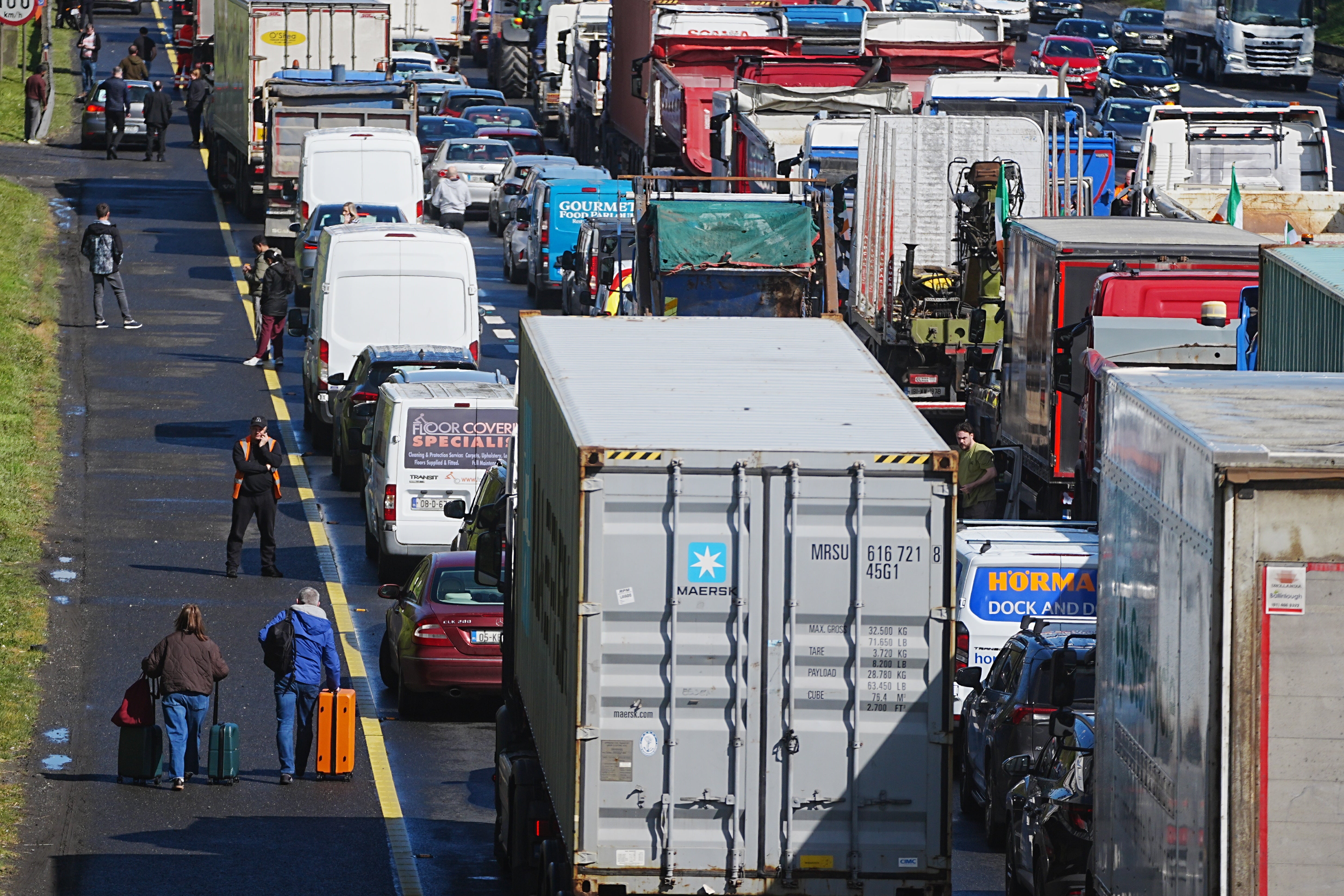 People with their luggage walk past the heavy traffic on Dublin’s M50 Northbound (Brian Lawless/PA)