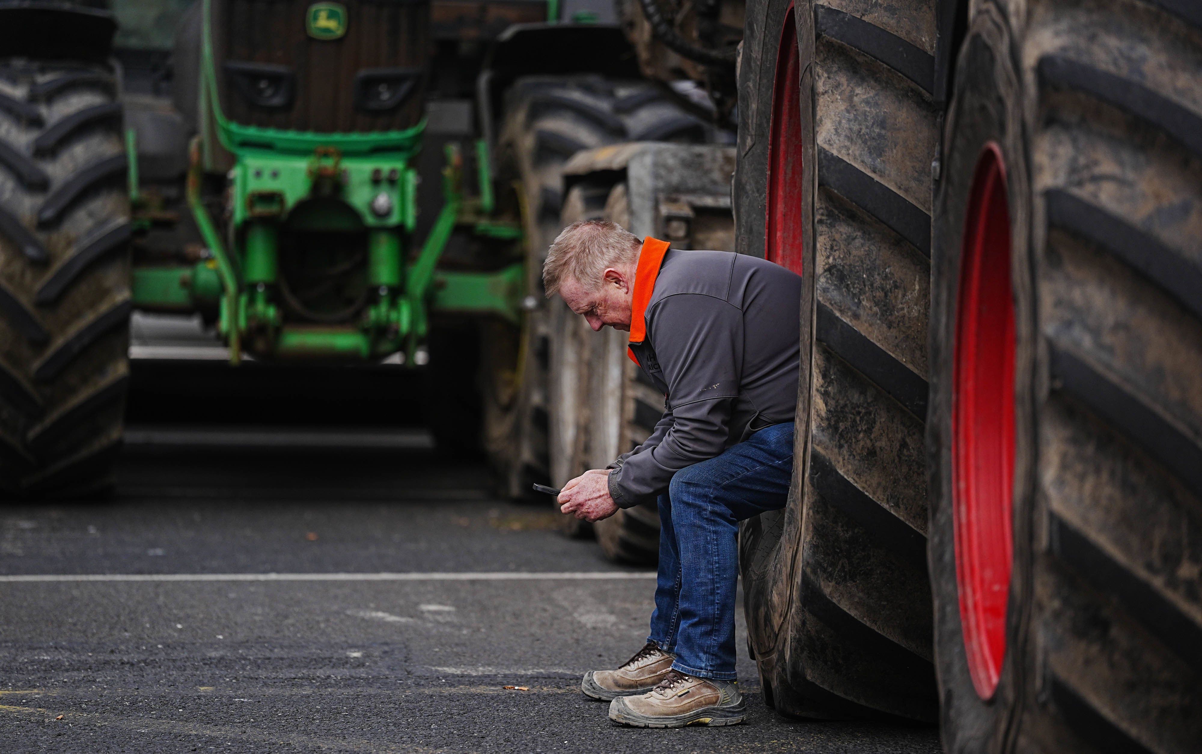 A man sits in a tractor wheel as vehicles are parked on O’Connell Street in Dublin (Brian Lawless/PA)