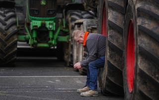 A man sits in a tractor wheel as vehicles are parked on O’Connell Street in Dublin (Brian Lawless/PA)