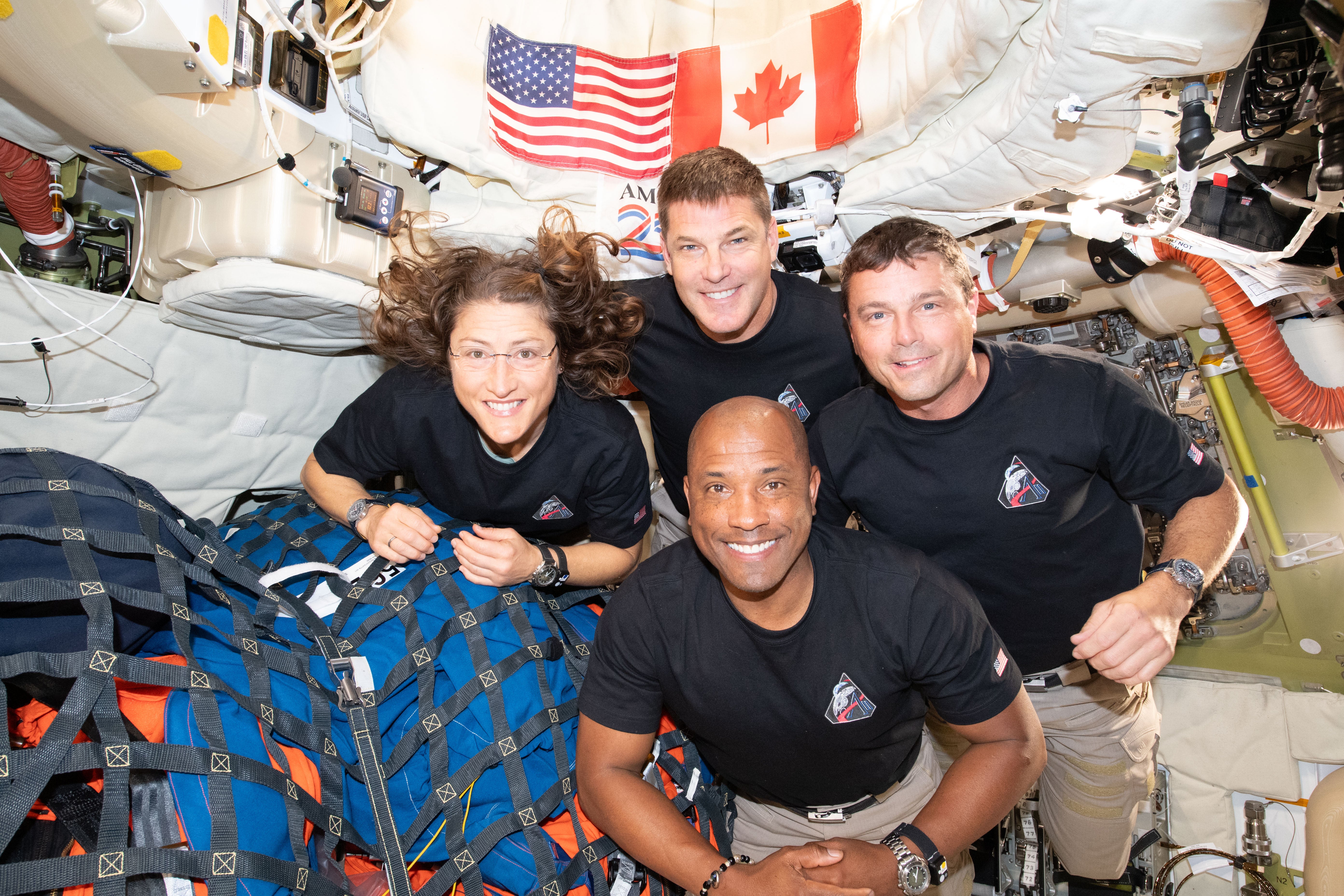 The Artemis II crew poses for a group photo inside the Orion spacecraft on their way home