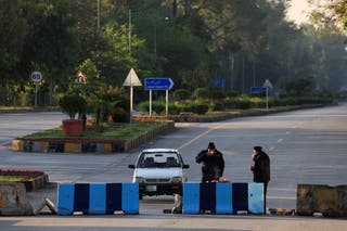 Police officers have their morning breakfast on a road blocked for security measures at the D Chowk area, near the President's house, as Pakistan prepares to host the U.S. and Iran for peace talks