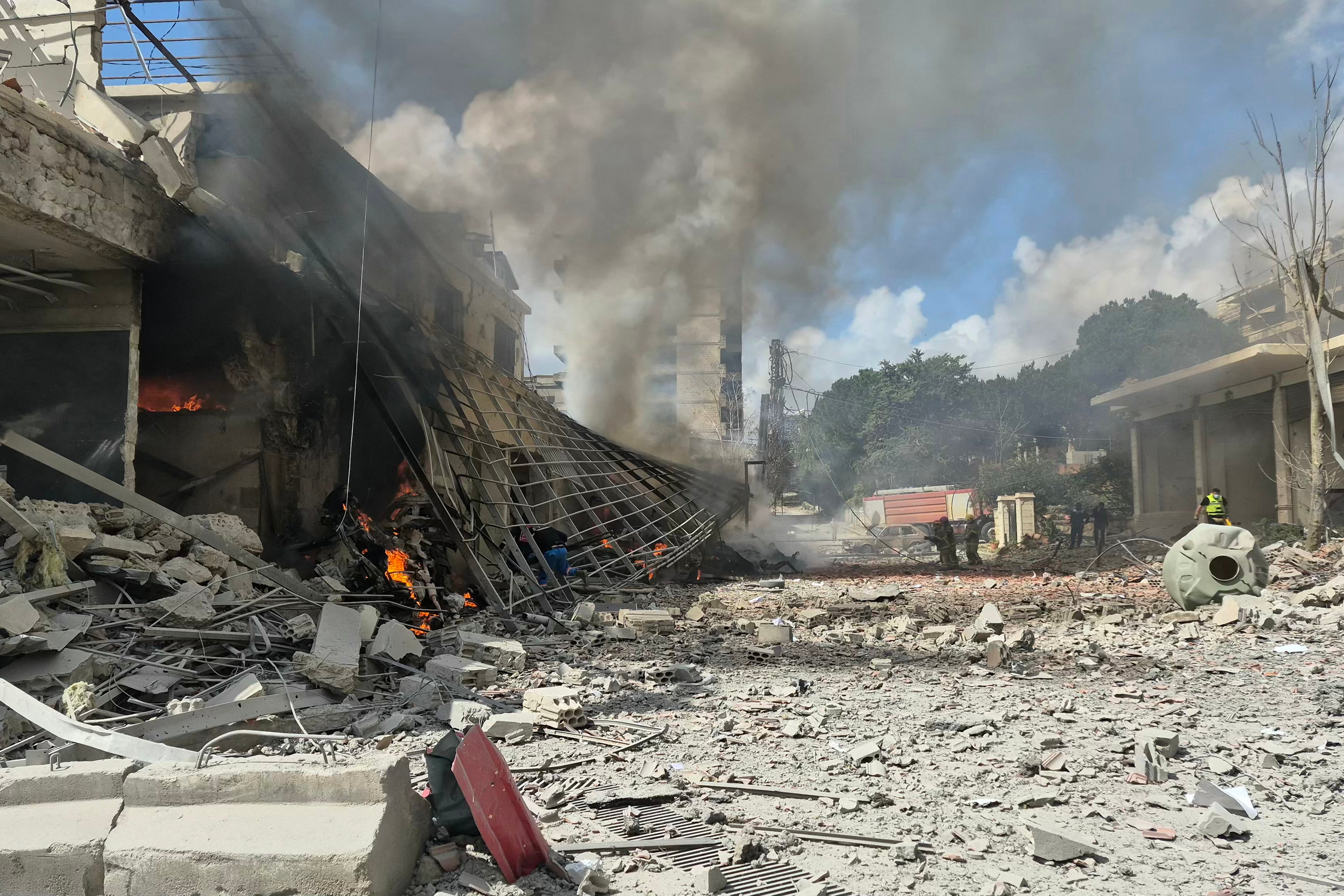 Сотрудники службы экстренного реагирования спешат к месту израильского авиаудара по ливанскому центру государственной безопасности в южном ливанском городе Набатия в пятницу.