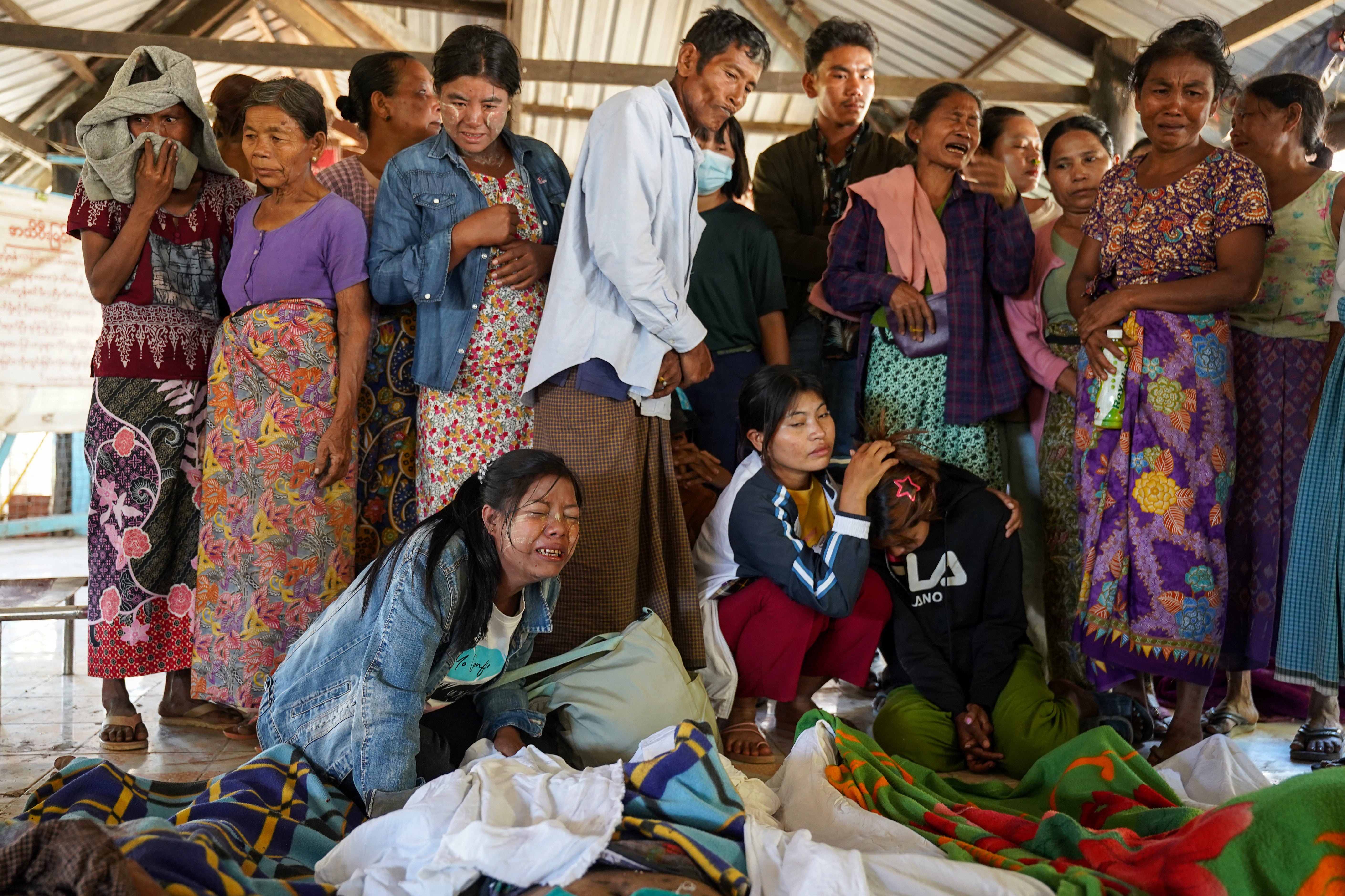 Mourners grieve as bodies of victims are laid out at a cemetery before their burial following an airstrike at a hospital in Mrauk U in western Rakhine State on 11 December 2025