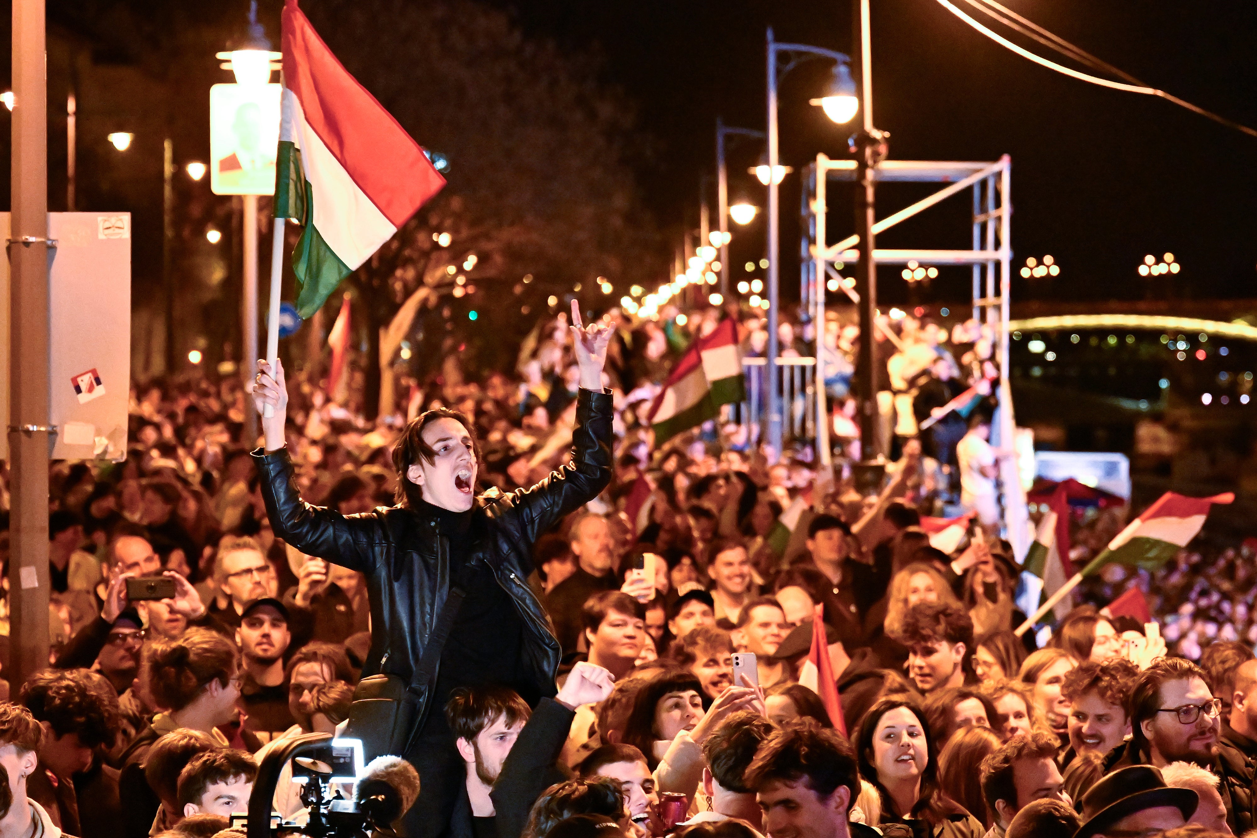 A man waves a Hungarian flag as he celebrates in the streets.