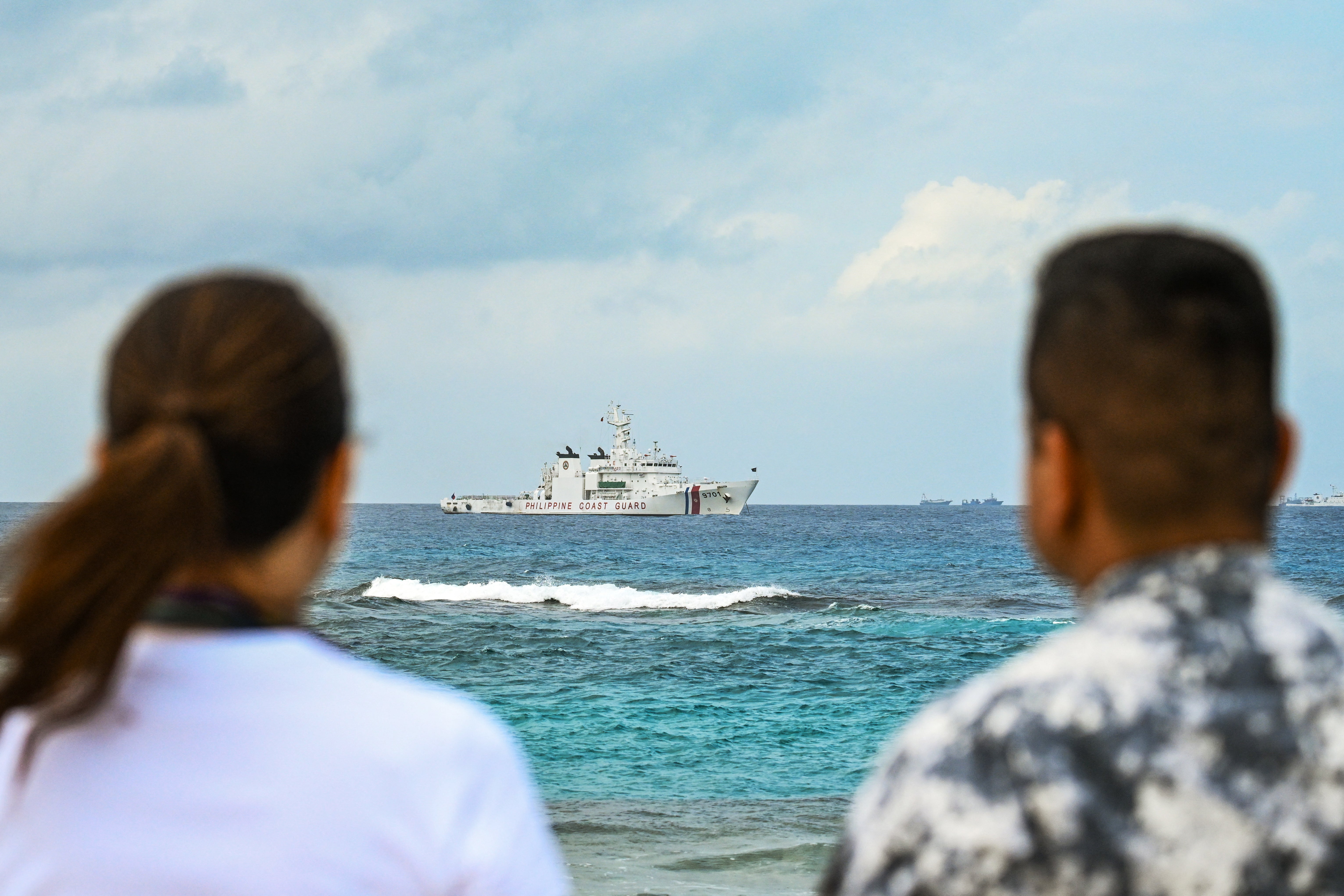 Philippine Senator Risa Hontiveros (L) and Commodore Jay Tarriela, spokesperson of Philippine Coast Guard for the South China Sea, look at a Philippine Coast Guard ship from Thitu Island in the South China Sea on February 21, 2026