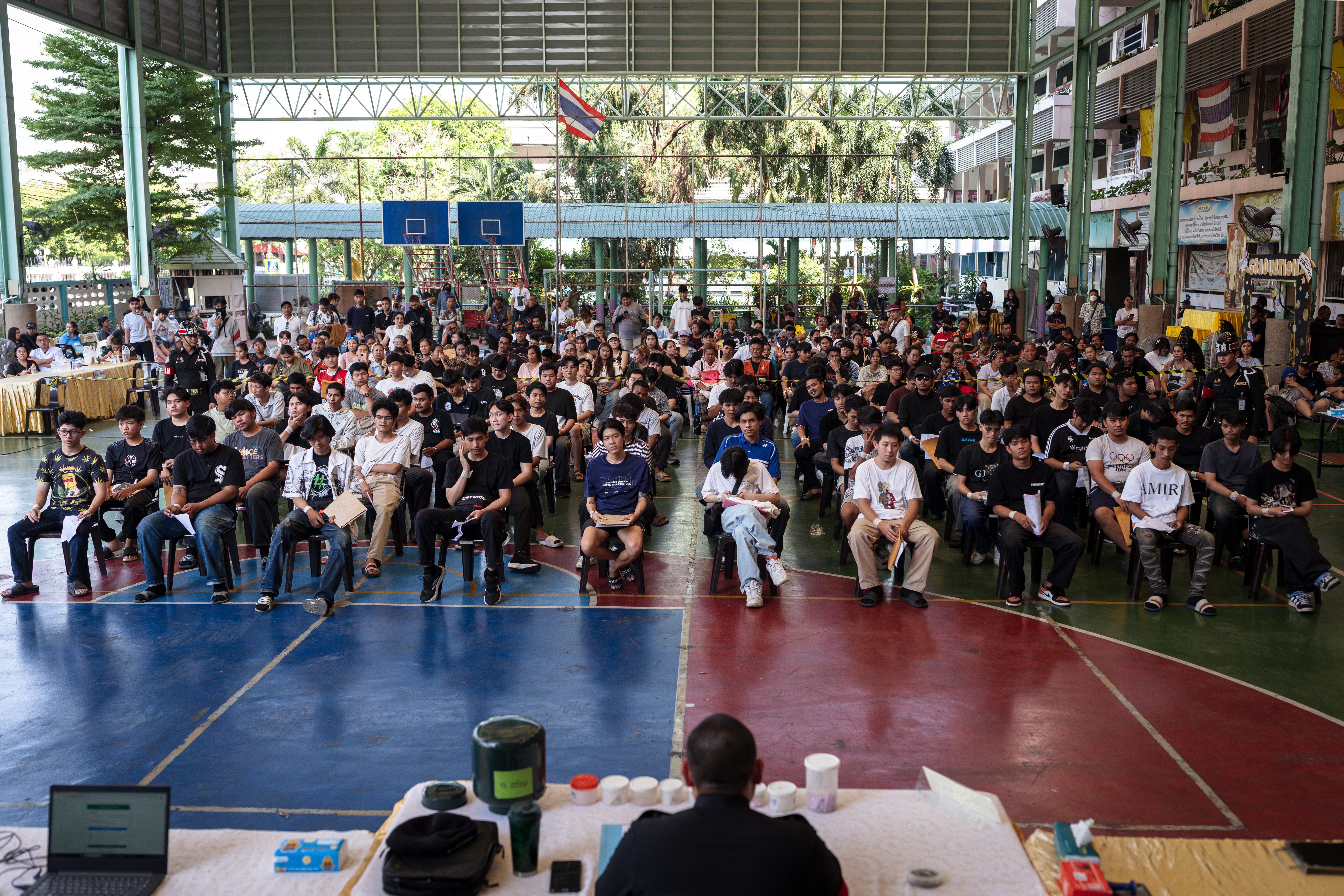 Men wait for the drawing of the Thai military conscription lottery at the Watmatchantikaram School in Bangkok on 7 April 2026