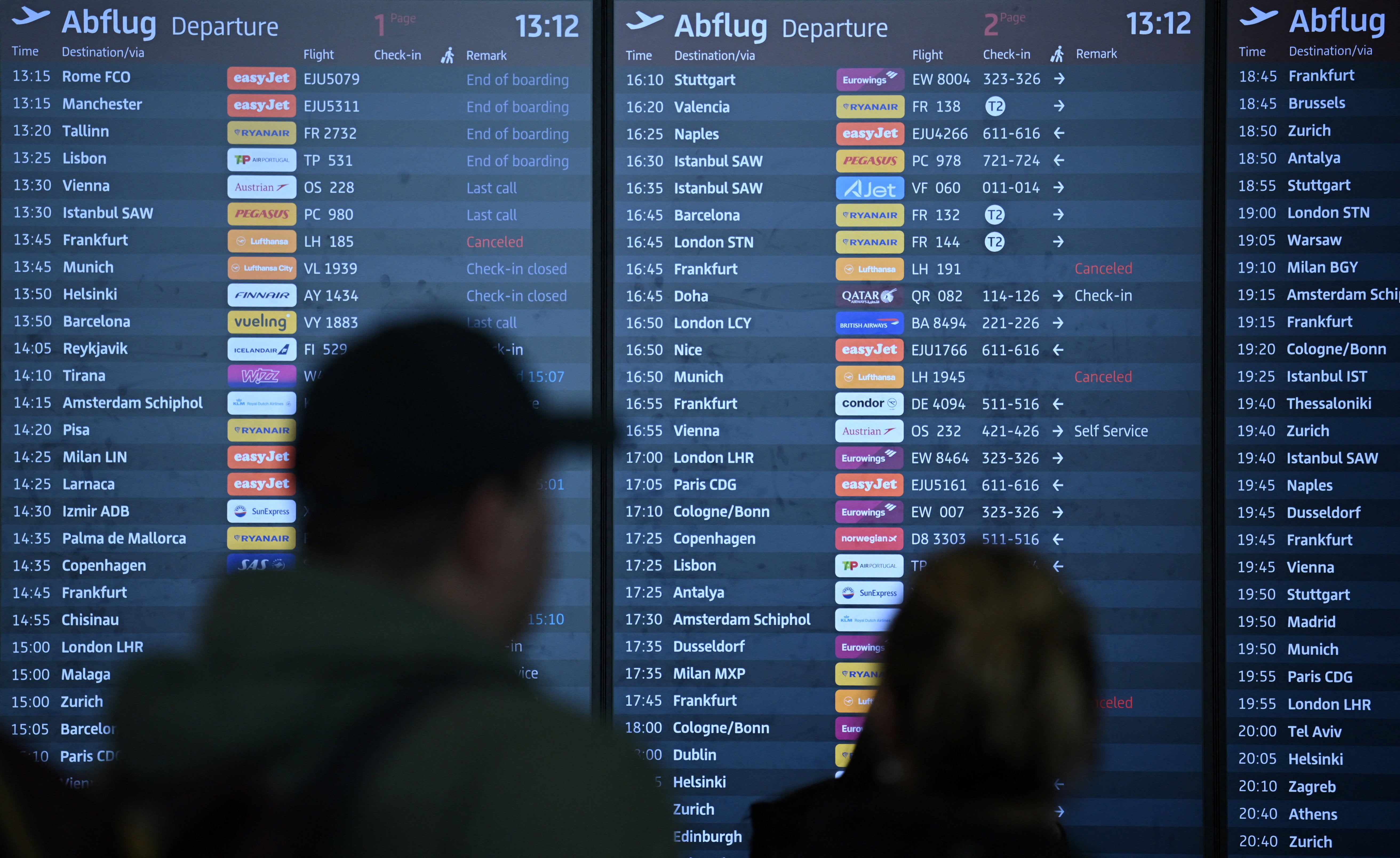 People walk past an information panel, showing cancelled Lufthansa flights during a strike of Cockpit, the union representing Lufthansa pilots.