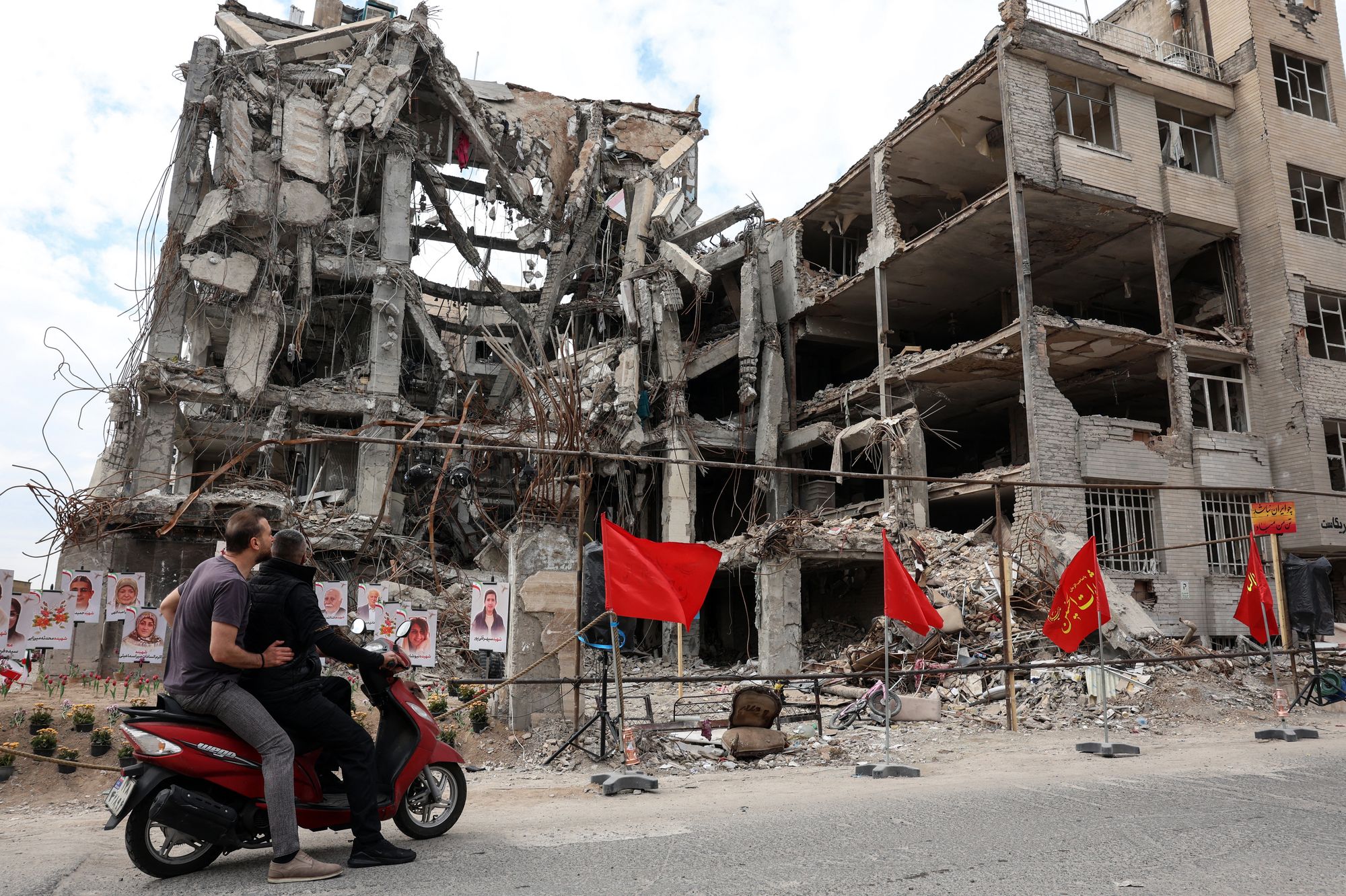 Iranians look at portraits of victims killed in the war in Tehran on April 13, 2026