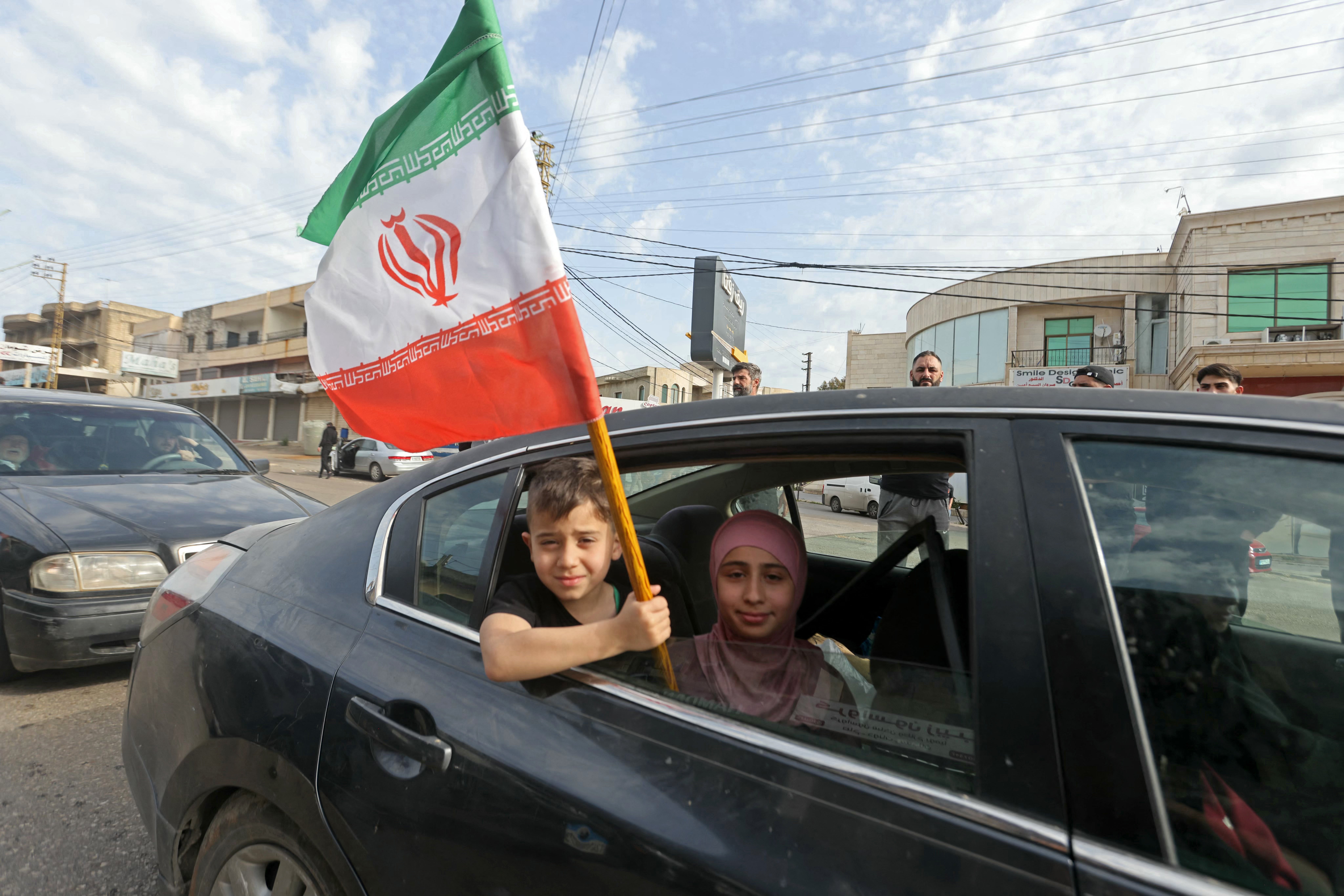 A boy holds an Iranian flag as he returns back to the southern Lebanese town of Marwanieh on April 17, 2026