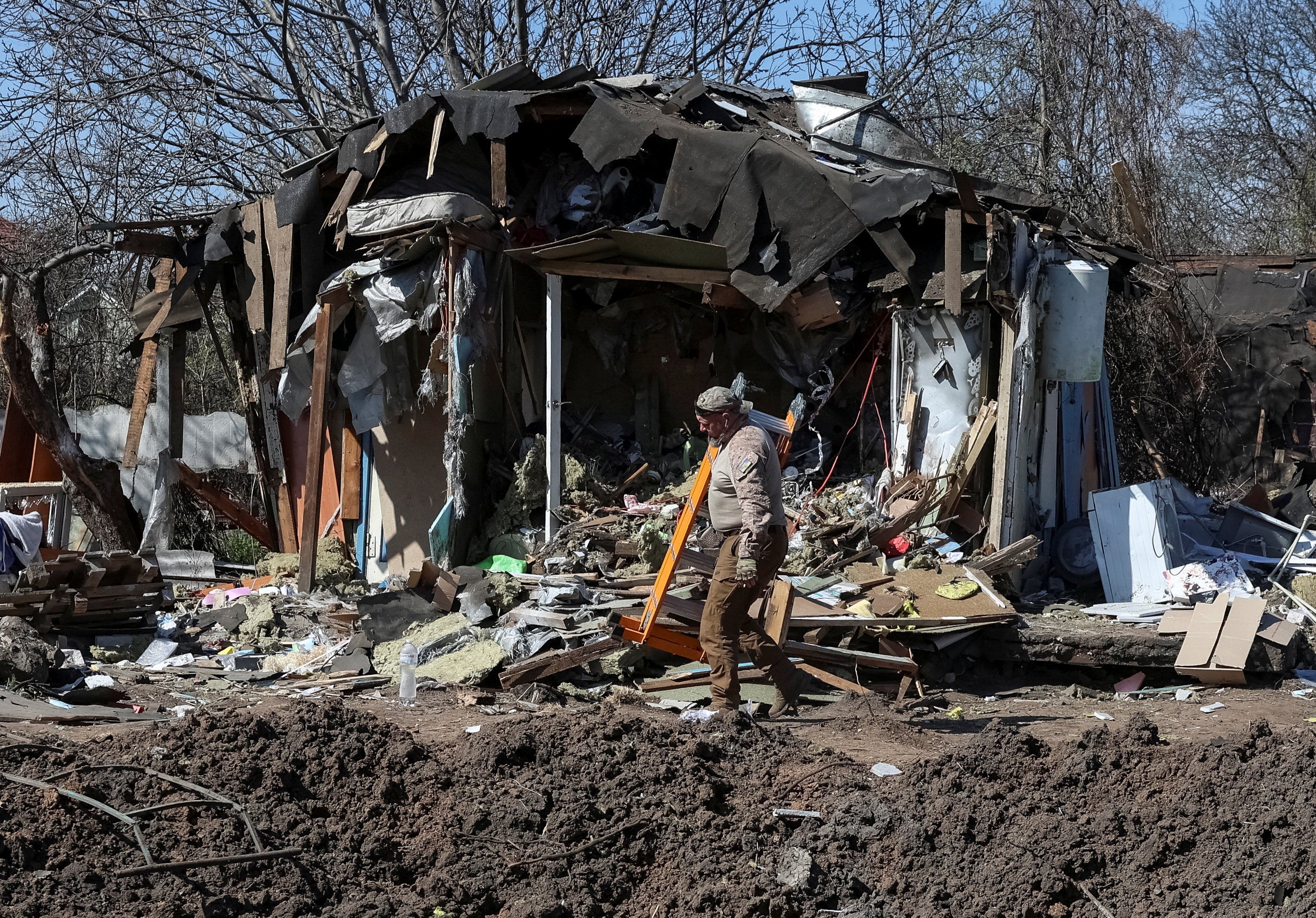 A worker walks at a site of a building hit by a Russian missile and drone strike, in Kyiv, 17 April