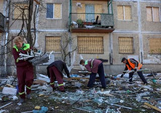 Workers clean an area at a site of an apartment building hit by a Russian strike in Kyiv, on Friday