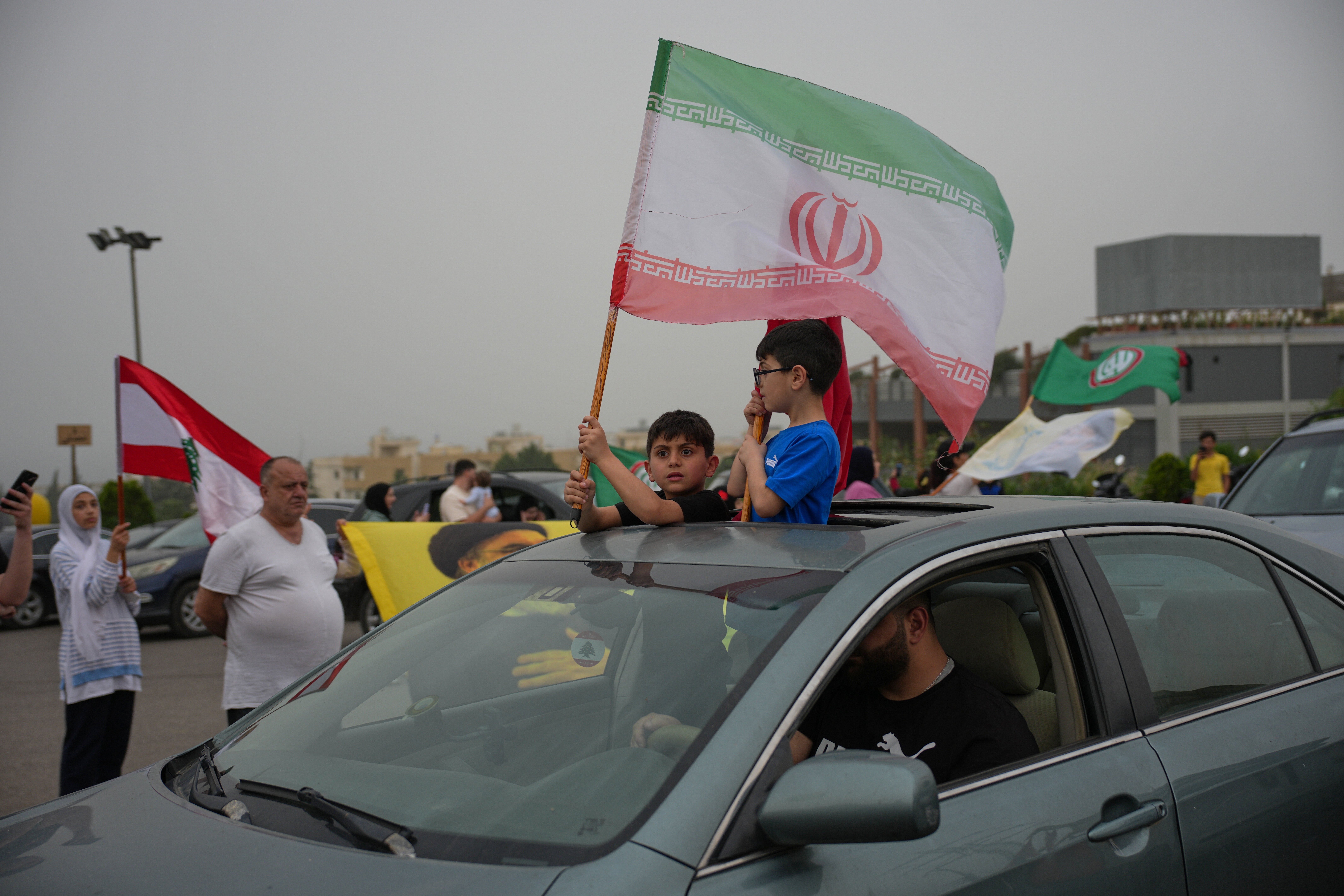Displaced residents hold Iranian and Lebanese flags as they drive back to their villages, in Jiyeh, near Saida, southern Lebanon, Friday, April 17, 2026, following a ceasefire between Israel and Hezbollah.