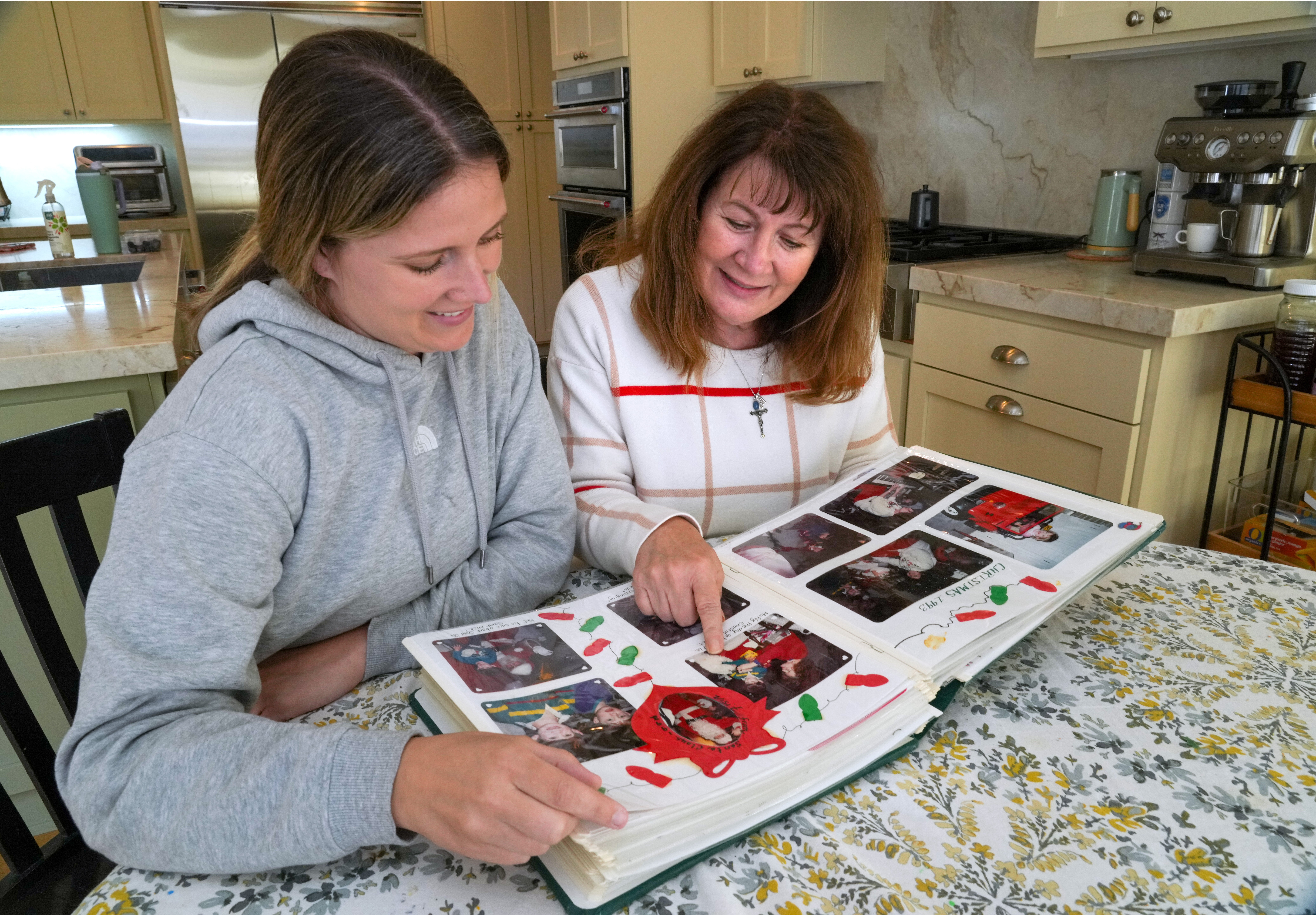 Kelley Nalewaja, right, looks over photos of her son, Michael Nalewaja, who died after unknowingly taking a lethal cocktail of fentanyl and carfentanil in November 2025, with her daughter, Caroline Bendel