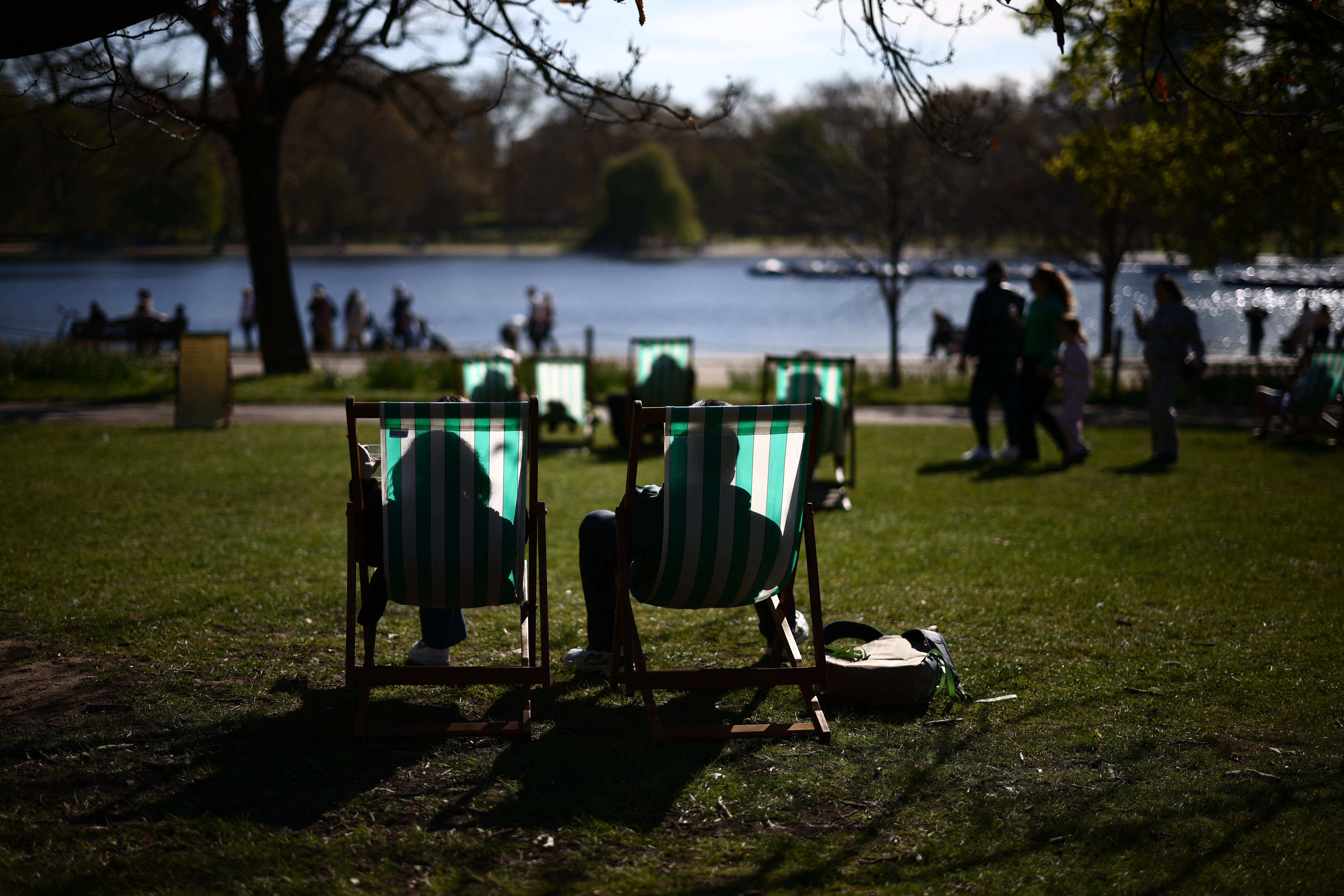 People sit on sun loungers on the banks of The Serpentine lake in Hyde Park, London