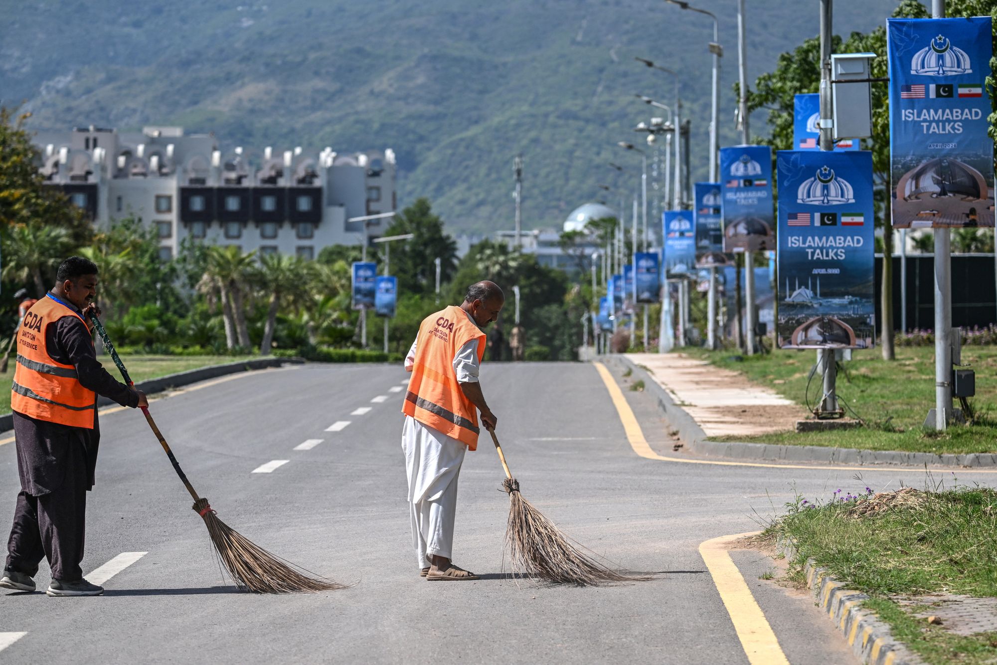 Sanitation workers sweep a road near the Serena Hotel in Islamabad