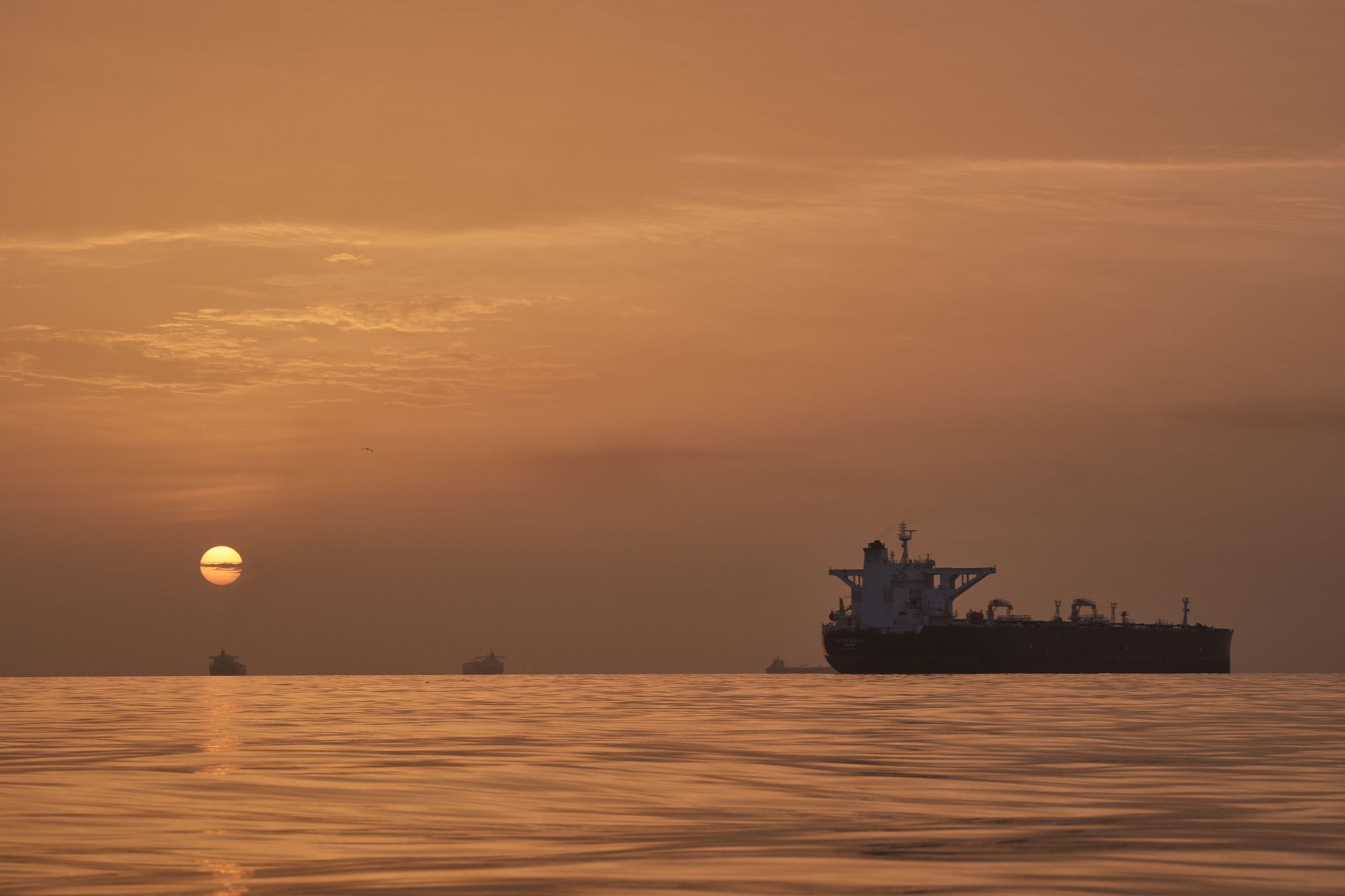 The sun rises behind tankers anchored in the Strait of Hormuz off the coast of Qeshm Island, Iran, Saturday, 18 April 2026