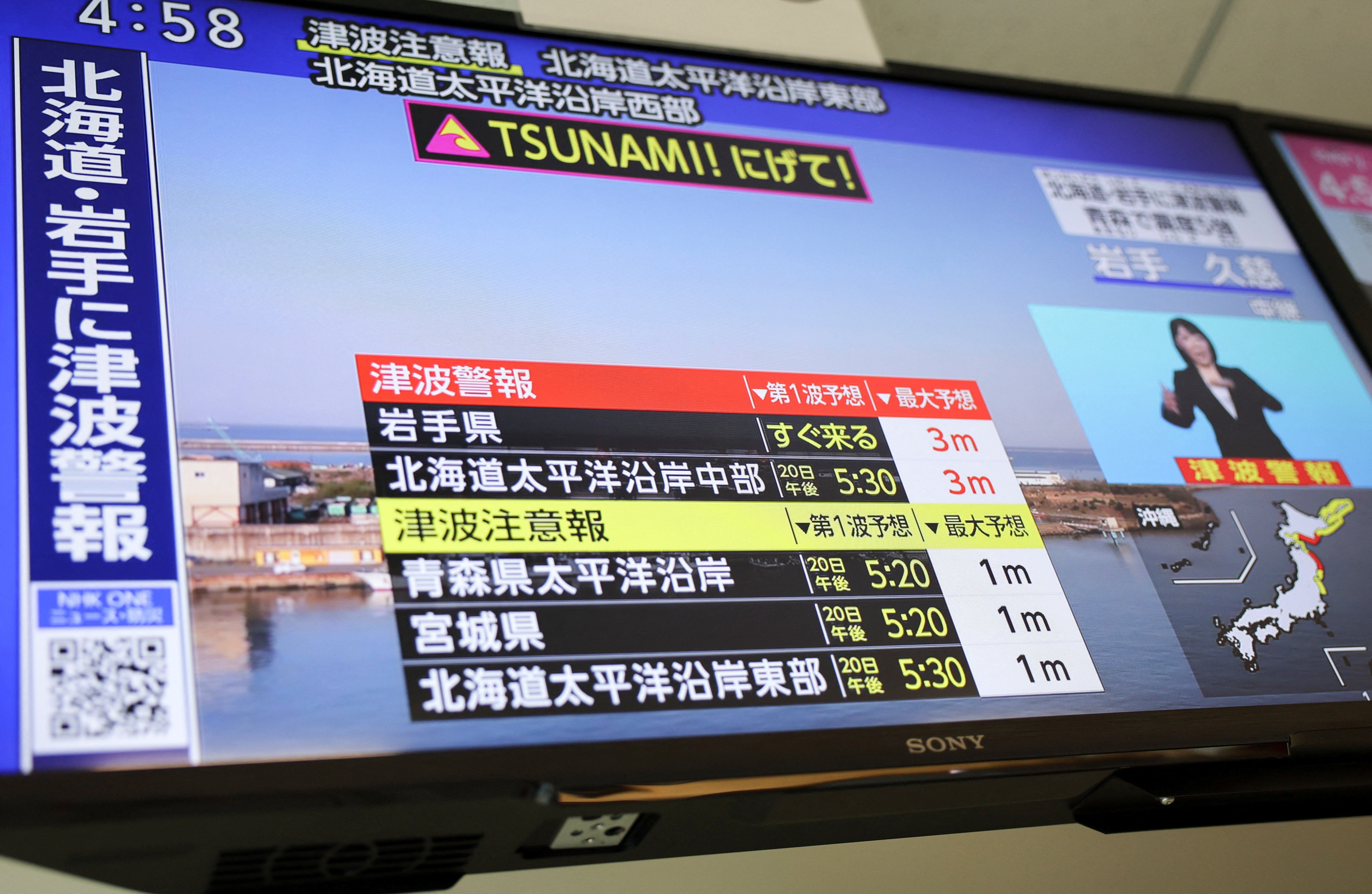 A television screen shows a news report on the Japan Meteorological Agency's tsunami warning