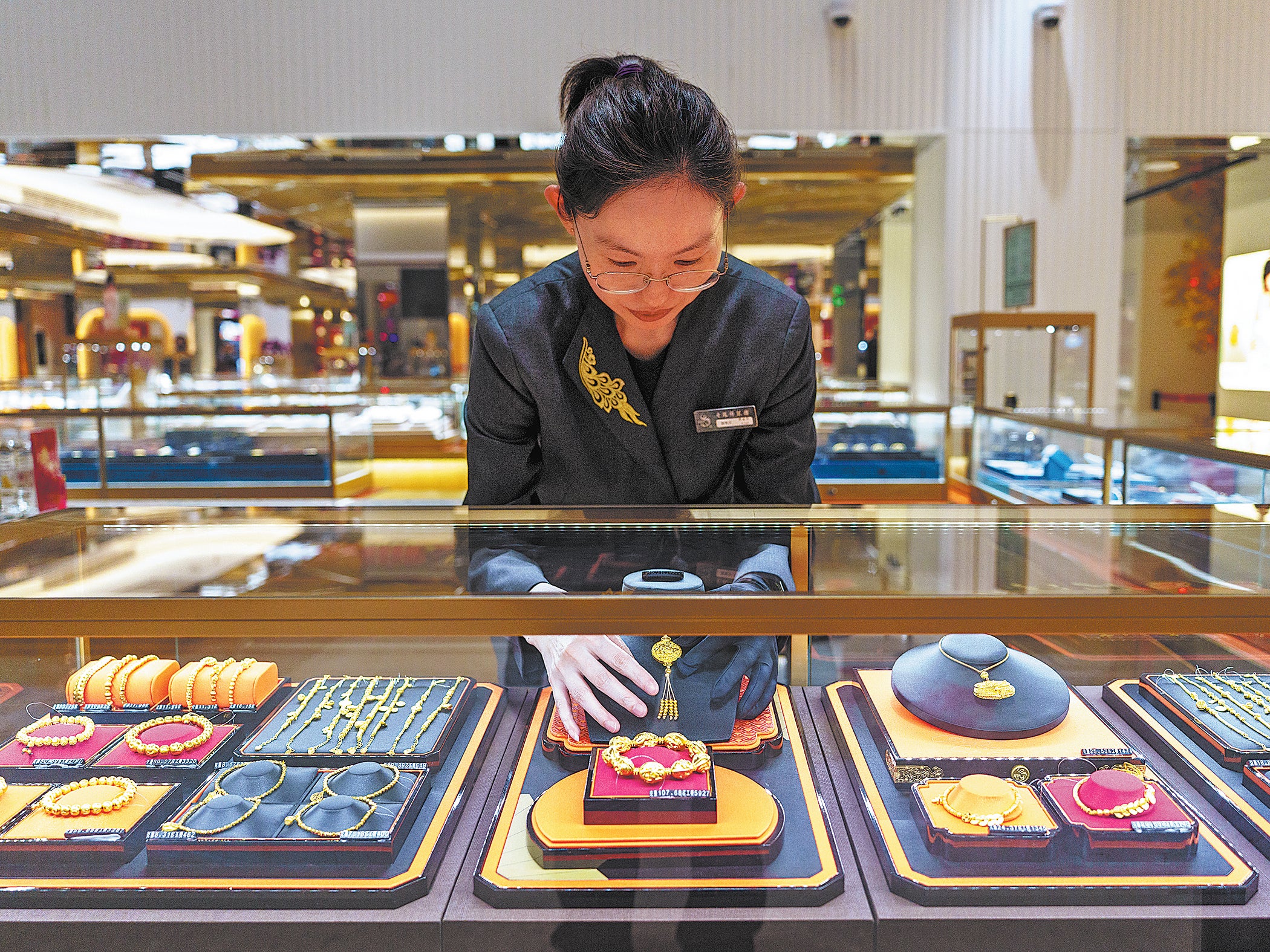 A shop assistant arranges gold jewellery at a Lao Feng Xiang store in Shanghai on 9 April