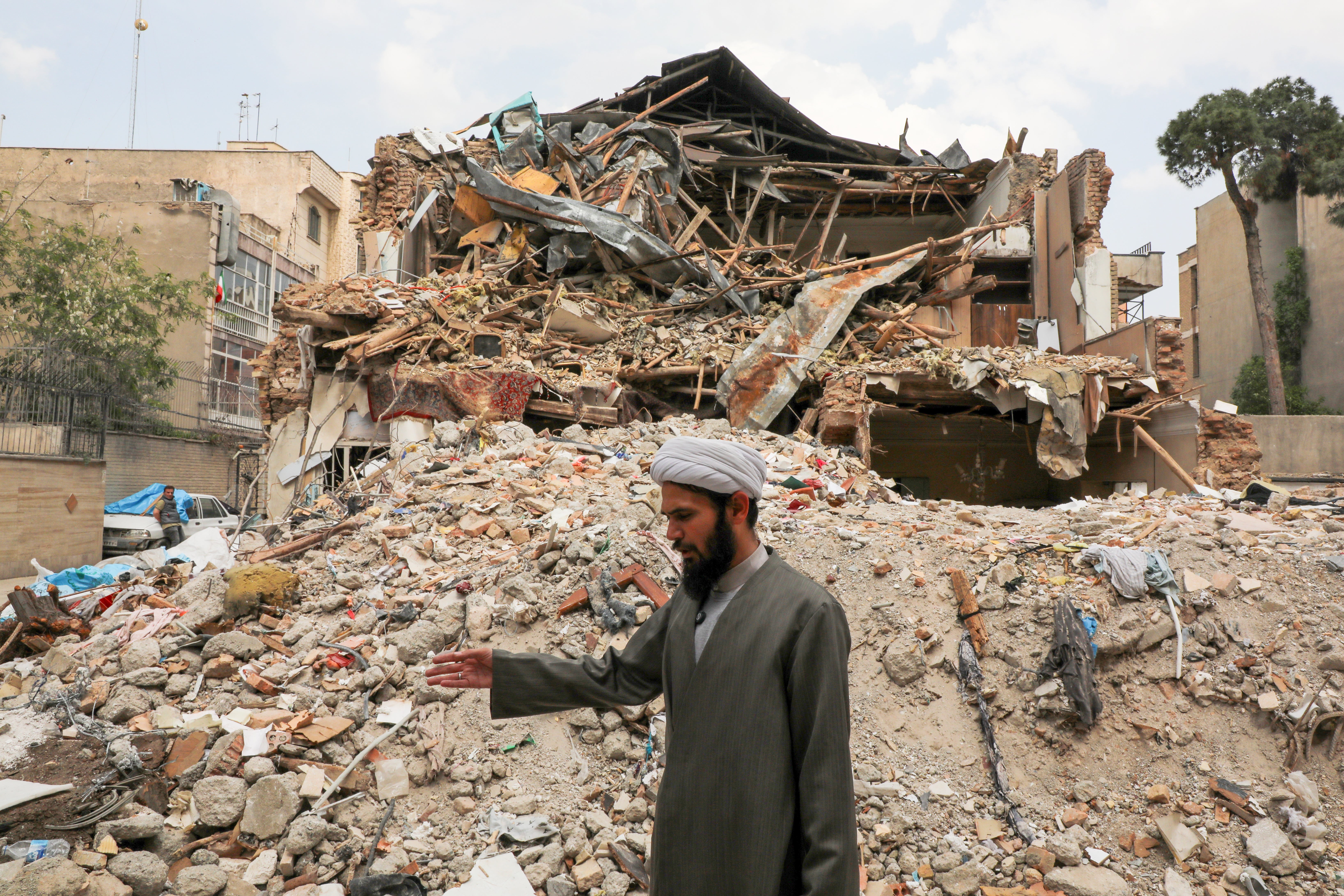 A cleric stands among the ruins of a Jewish synagogue that was previously damaged during US-Israeli strikes