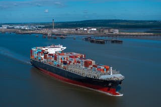 Container ship Nansha Express makes its way towards Antwerp on the River Thames past the The Oikos bulk liquid fuel storage facility
