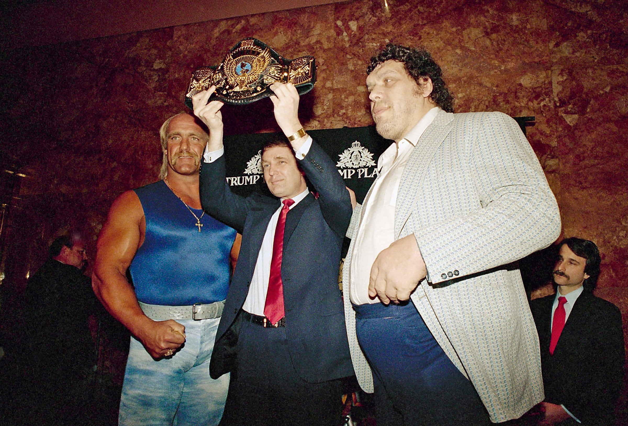 Donald Trump holds the World Wrestling Federation Championship belt flanked by Hulk Hogan, left, and Andre the Giant at a news conference, March 15, 1988