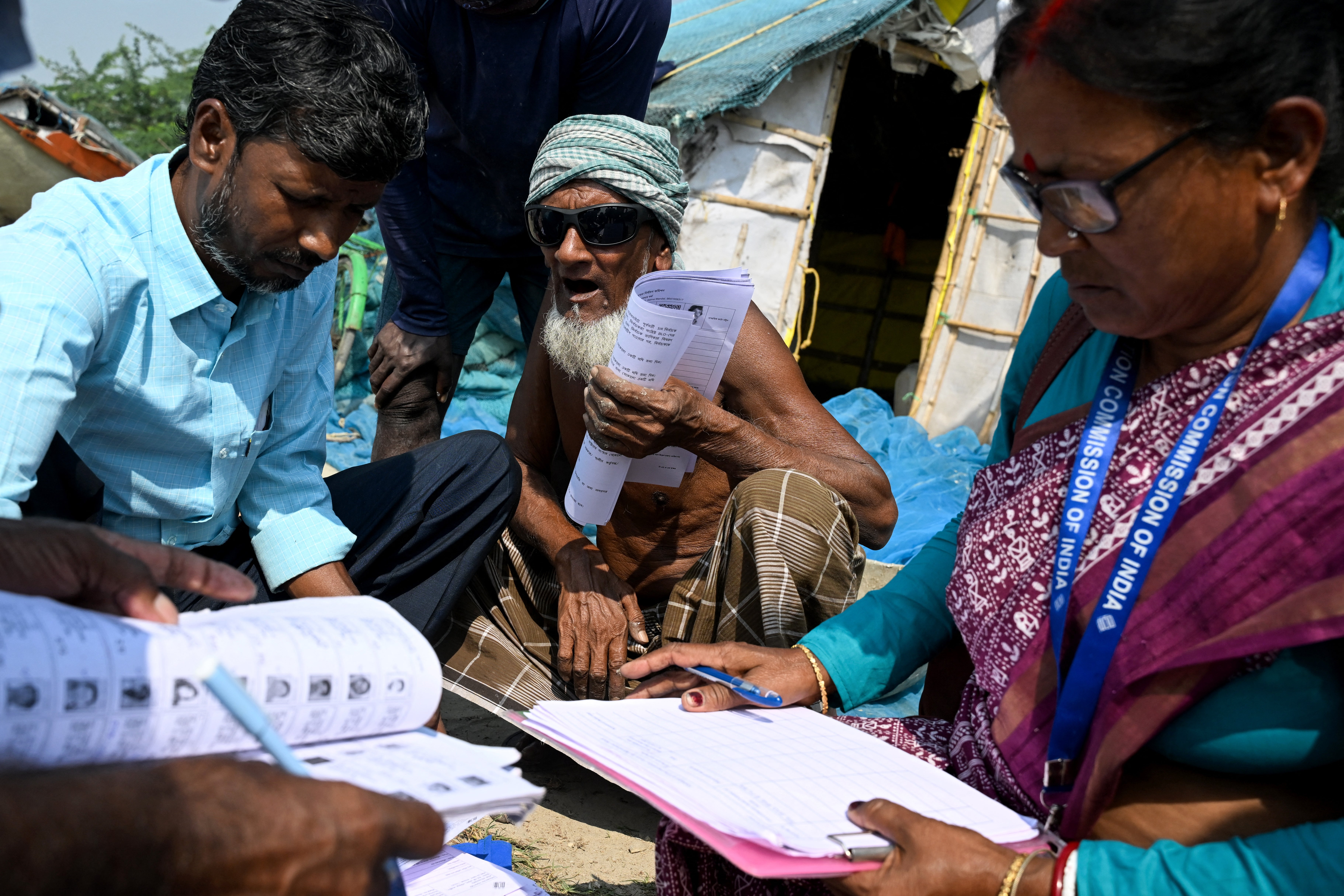 Officials distribute enumeration forms as a part of the election commission’s Special Intensive Revision (SIR), at a fishing village on Mousuni Island