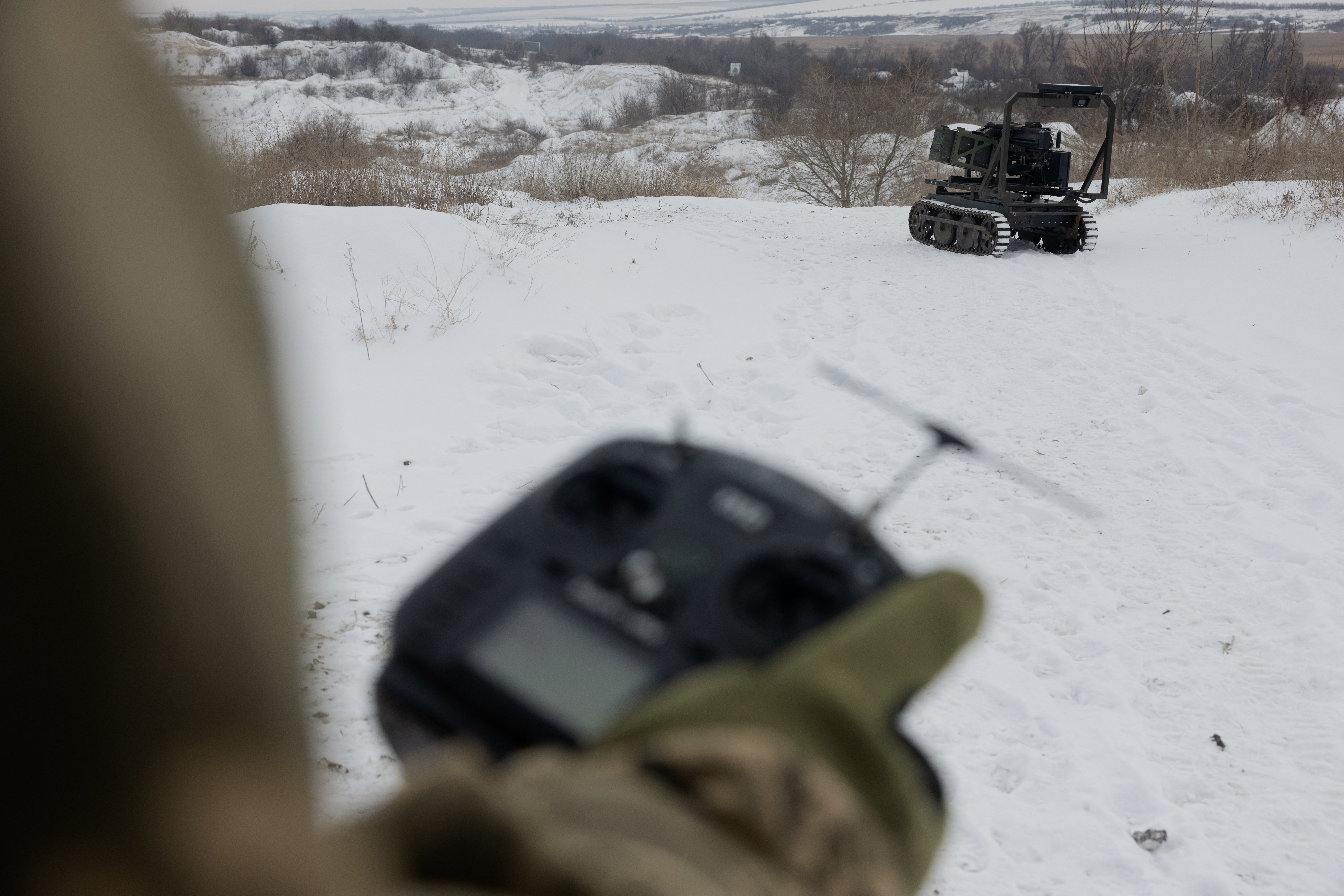 A Ukrainian serviceman of the 30th separate mechanized brigade tests an unmanned robotic ground vehicle armed with an Mk 19 grenade launcher