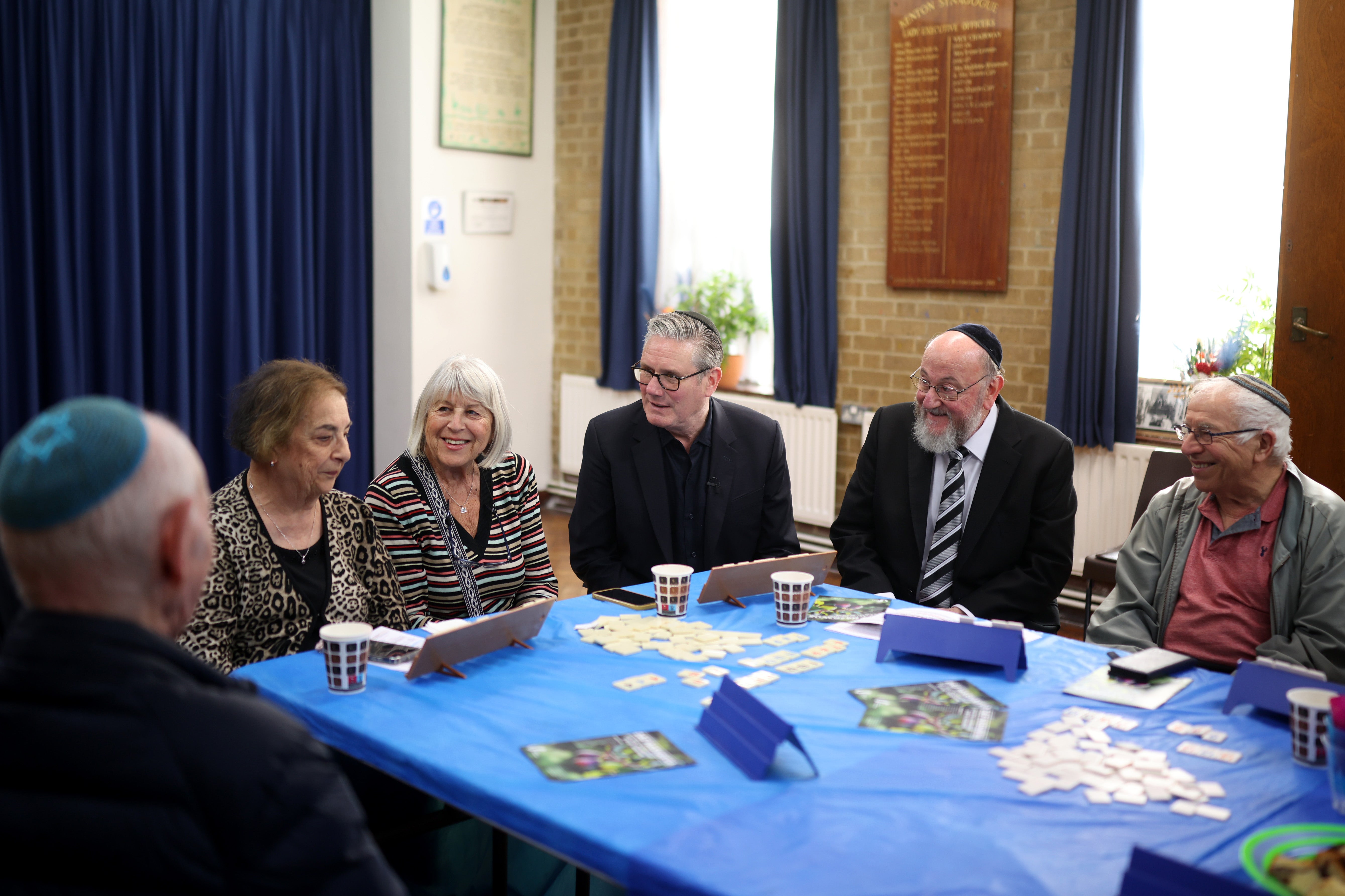 Sir Keir Starmer speaks as Chief Rabbi Ephraim Mirvis (2nd right) reacts while they join people during a visit Kenton United Synagogue