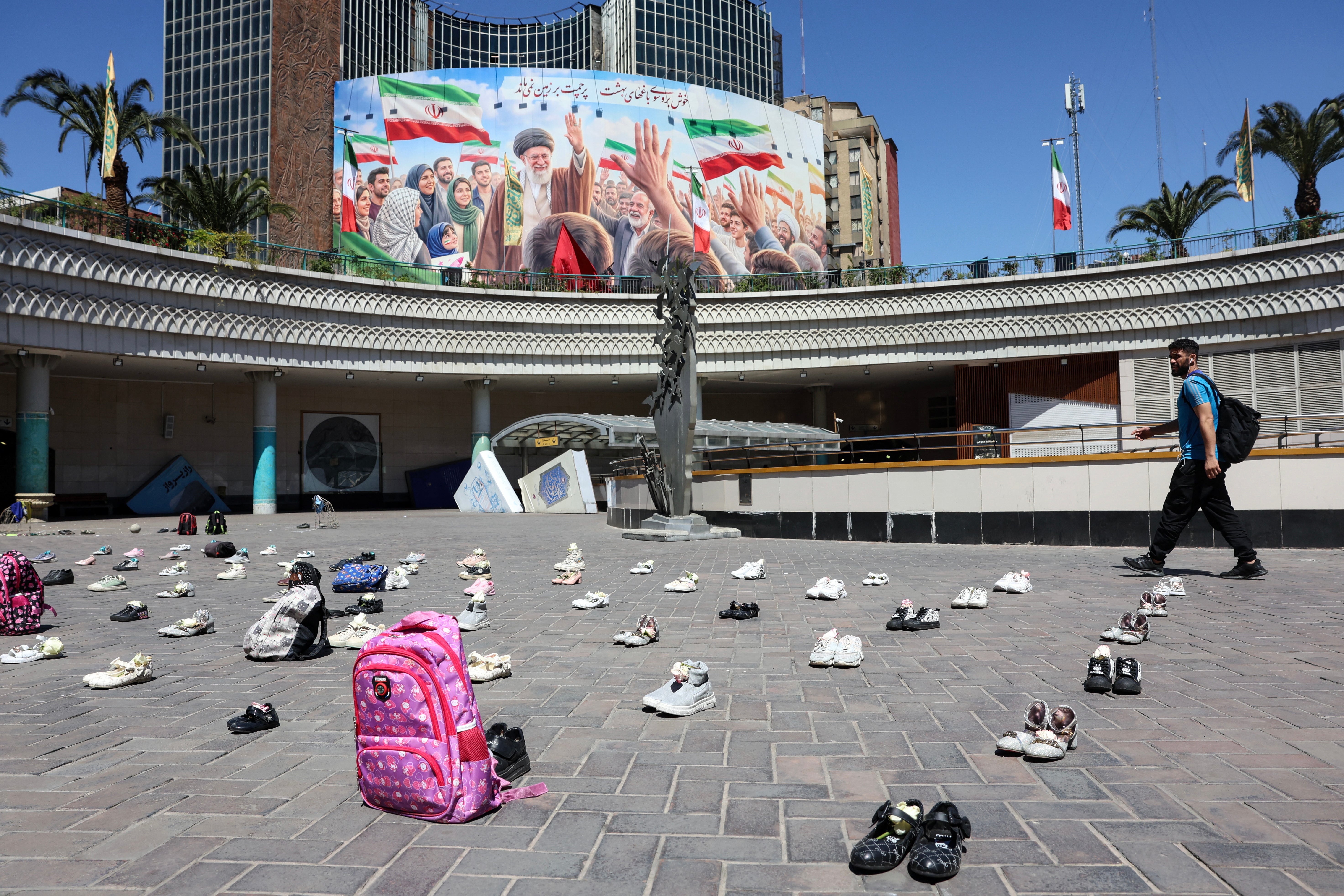 An Iranian man walks past symbolic belongings laid on the ground at Valiasr Square in Tehran on 24 April 2026, in tribute to the schoolgirls in Minab killed in an airstrike during US-Israeli attacks