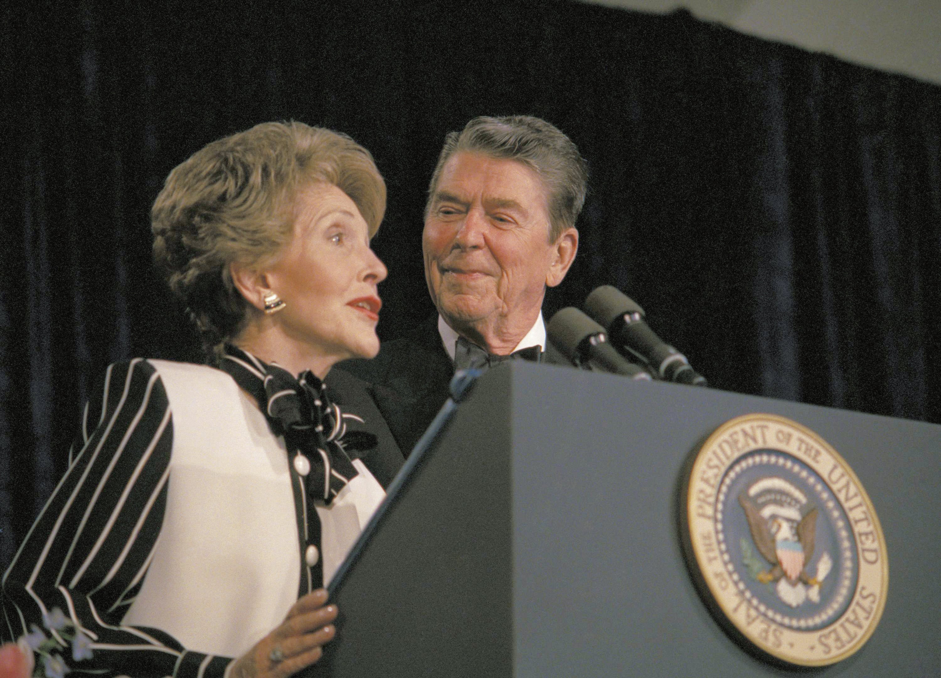 President Ronald Reagan watches as first lady Nancy Reagan comments from the podium during the White House Correspondents' Association annual dinner 1983