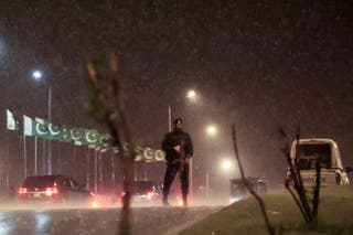 A police officer stands guard as the motorcade, believed to be carrying Iranian Foreign Minister Abbas Araghchi, arrives