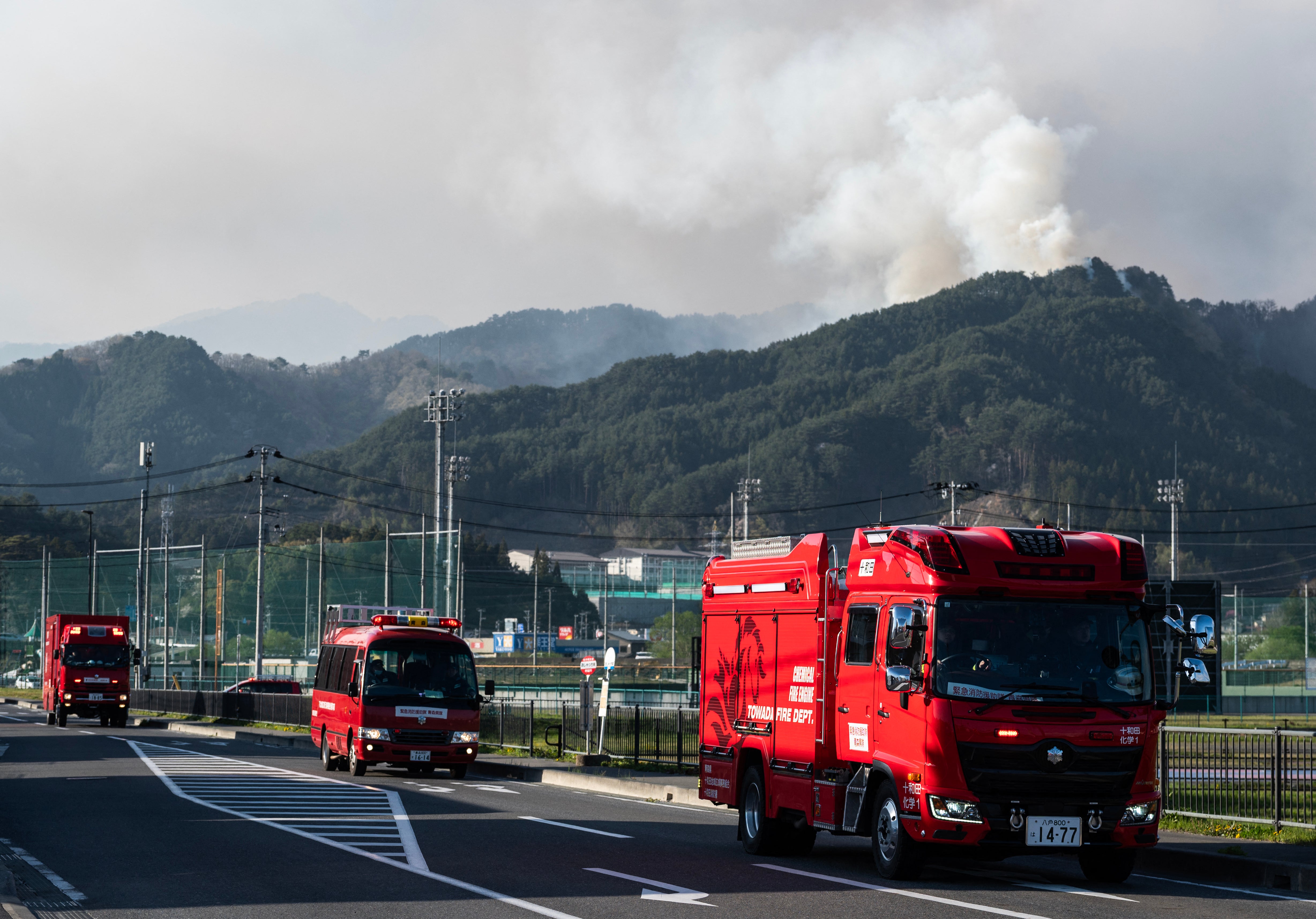 Fire trucks move to a new location as smoke is seen in the background in the town of Otsuchi in Iwate Prefecture