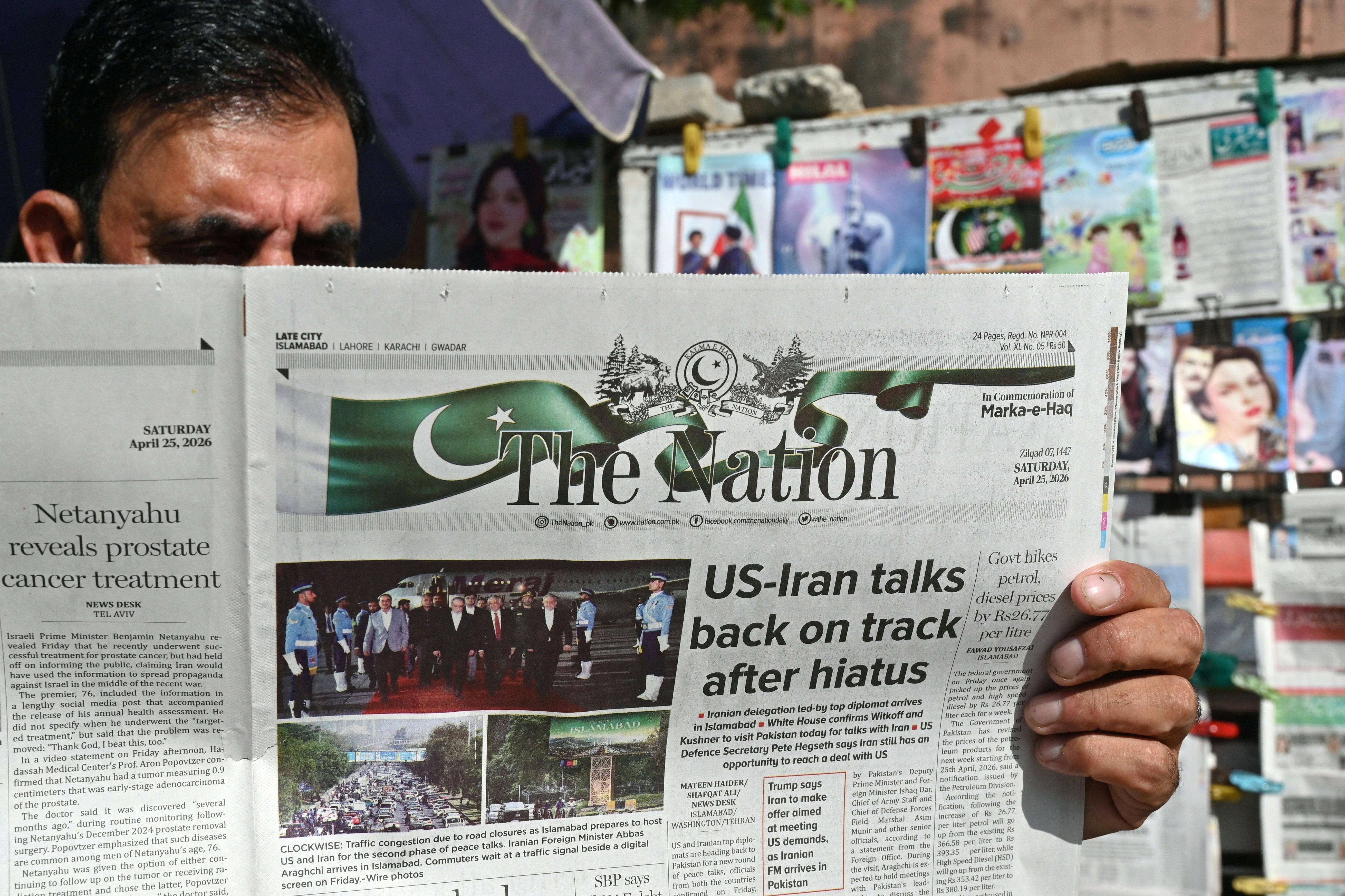 A man reads a newspaper at a roadside stall in Islamabad on April 25, 2026