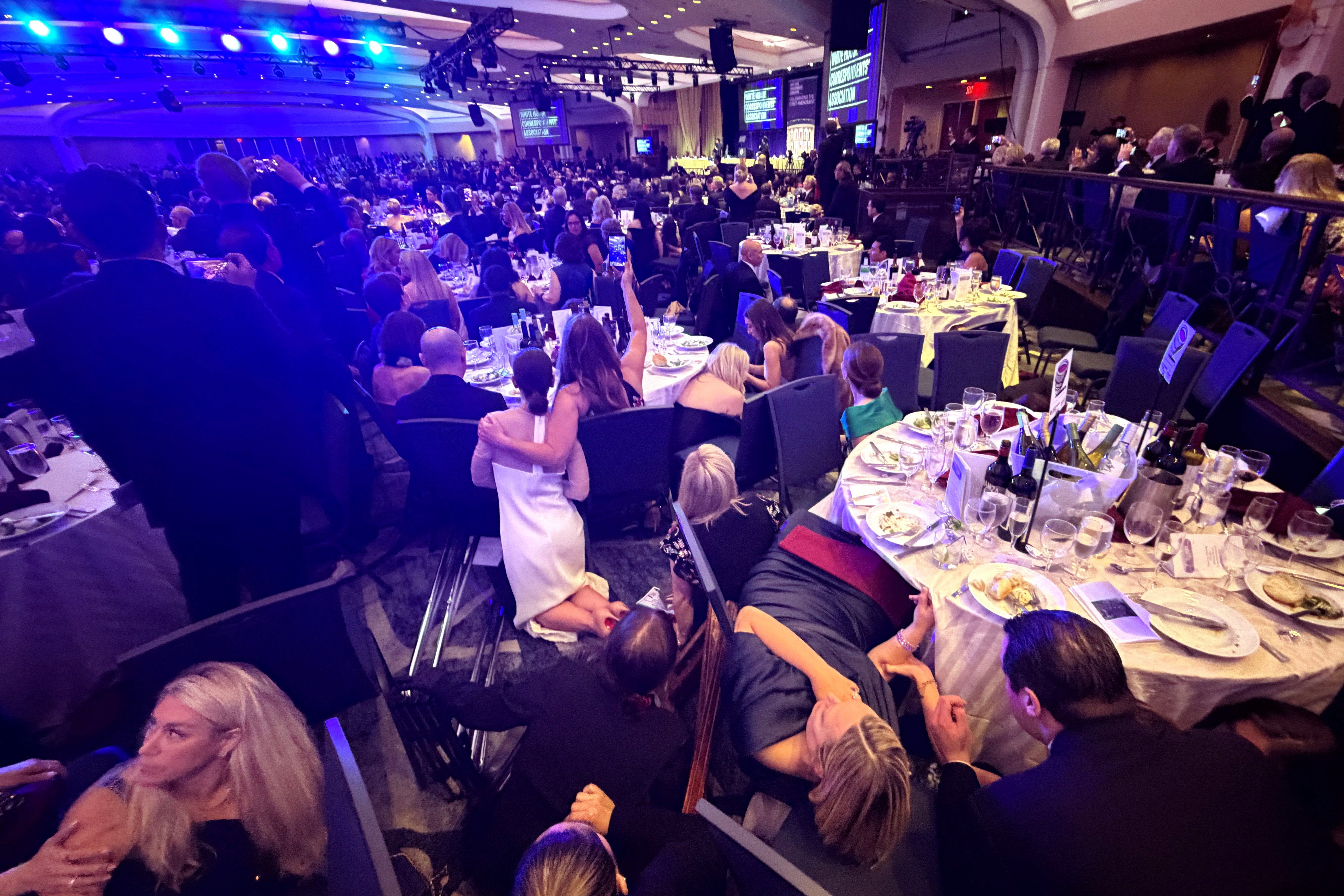 Members of the media take cover after a shooter opened fire at the White House Correspondents’ Dinner
