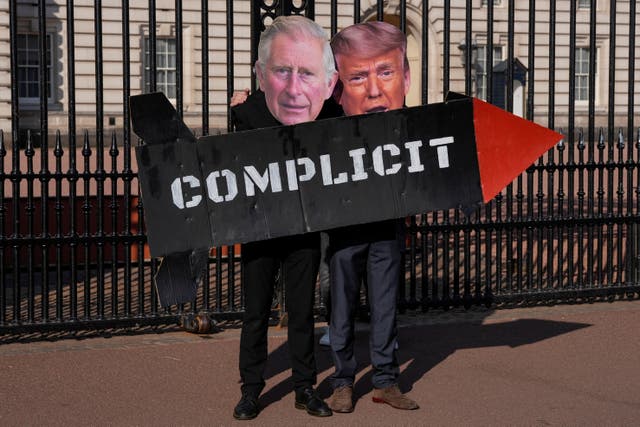<p>Dos miembros del grupo de acción Stop Trump Coalition posan con un misil de juguete y máscaras del rey Carlos III de Reino Unido y del presidente estadounidense Donald Trump frente a las puertas del palacio de Buckingham, en el centro de Londres</p>