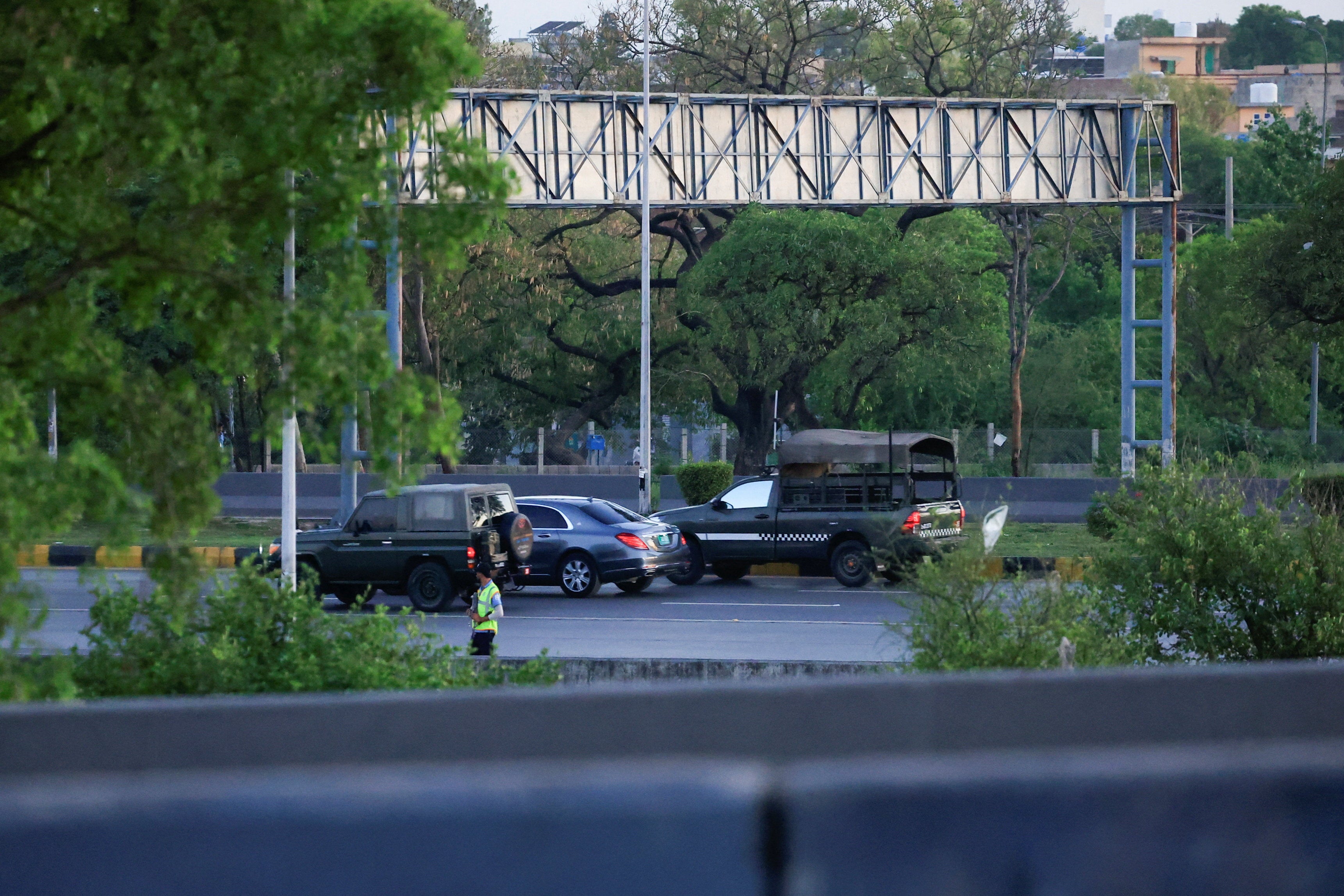 A police officer stands guard as a motorcade reportedly carrying Abbas Araghchi passes by in Islamabad