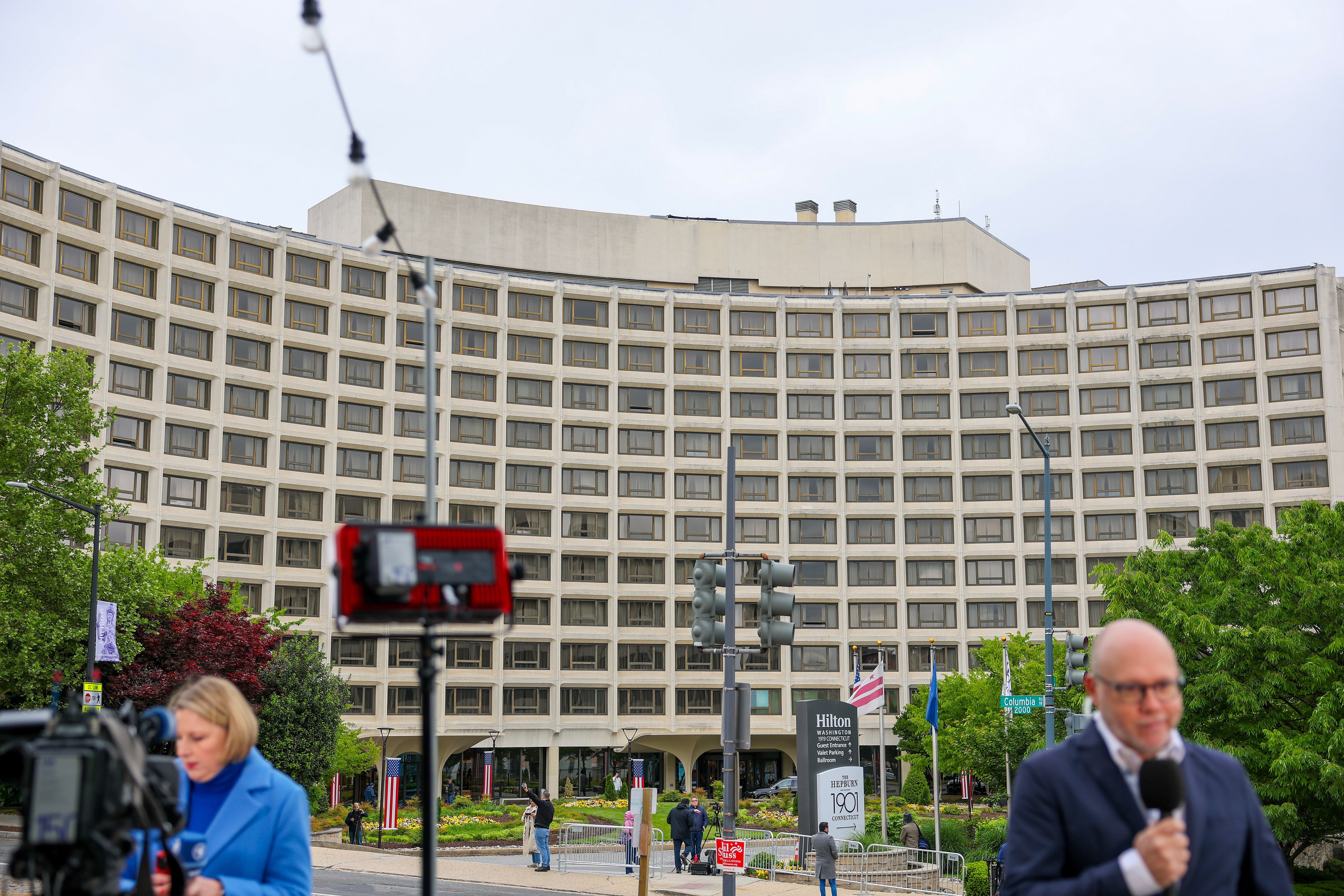Journalists report outside the Washington Hilton hotel one day after an attempted attack inside against the annual White House Correspondents' Association dinner