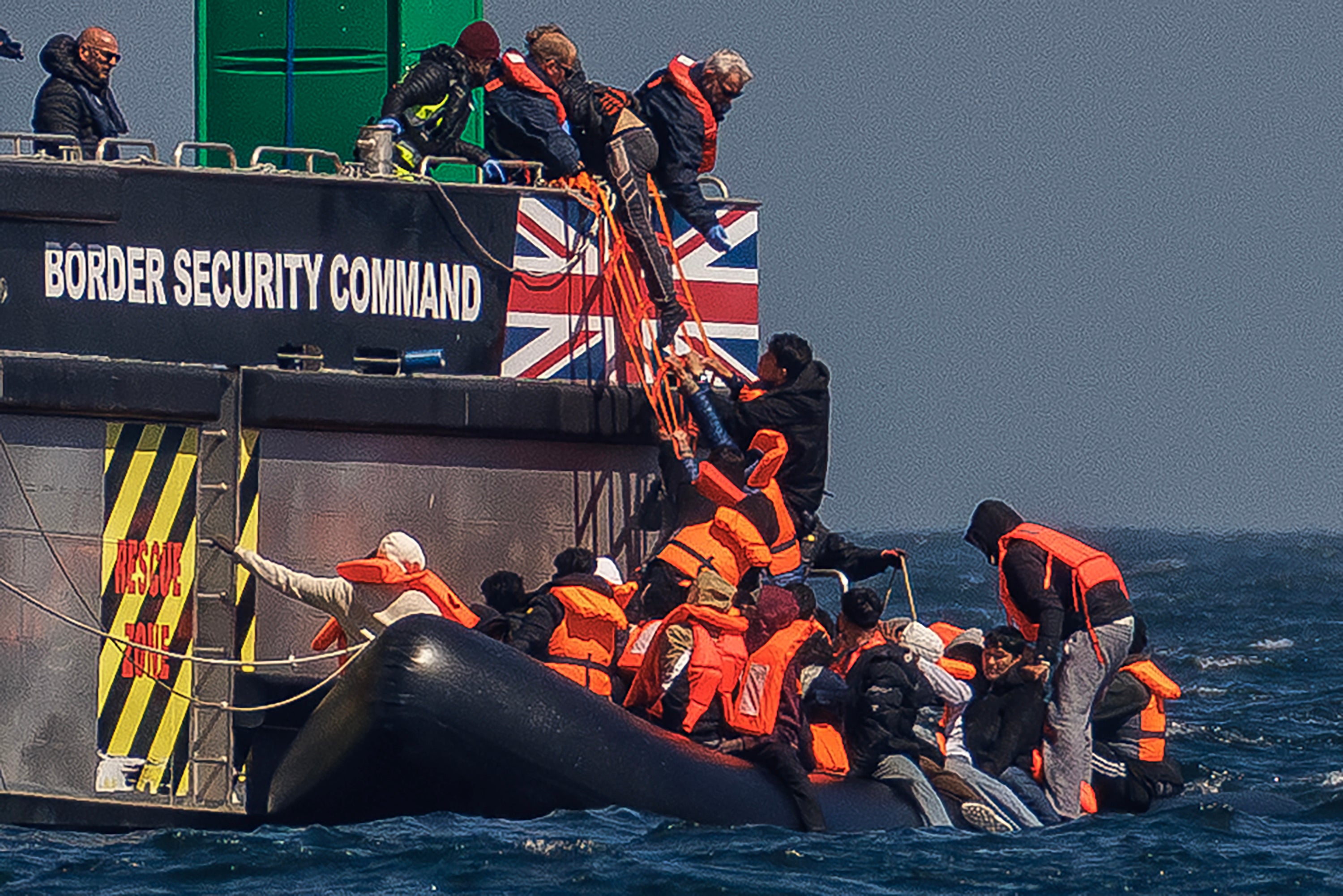 Migrants on an inflatable 'small boat' clamber on to The UK Border Force vessel, BSC Intrepid after crossing the channel from northern France on 27 April in Dover, England. AI facial age estimation technology will be used on migrants at the UK border. (Getty)