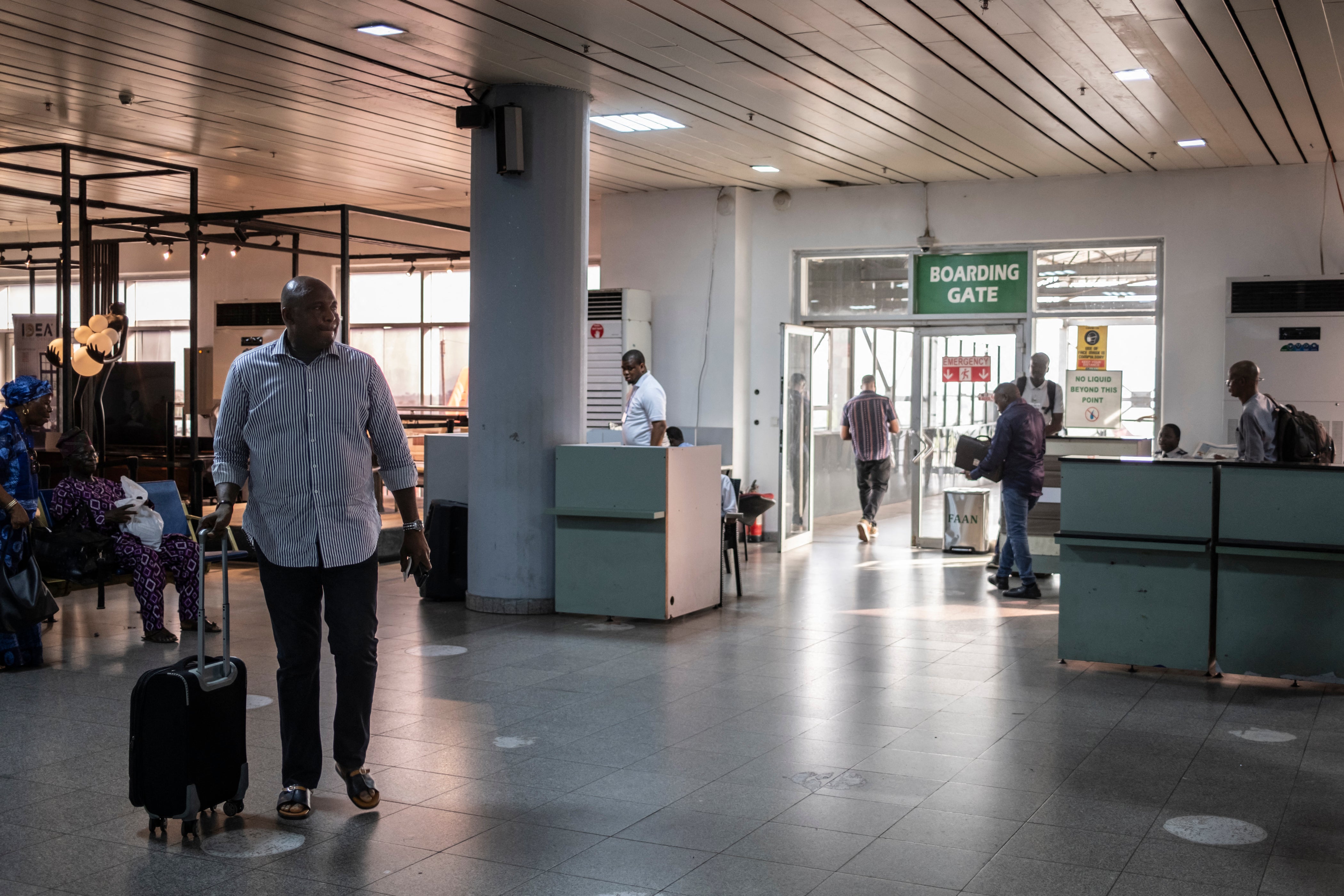 Passengers wait to board their flight at an airport boarding gate at Nnamdi Azikiwe International in Abuja