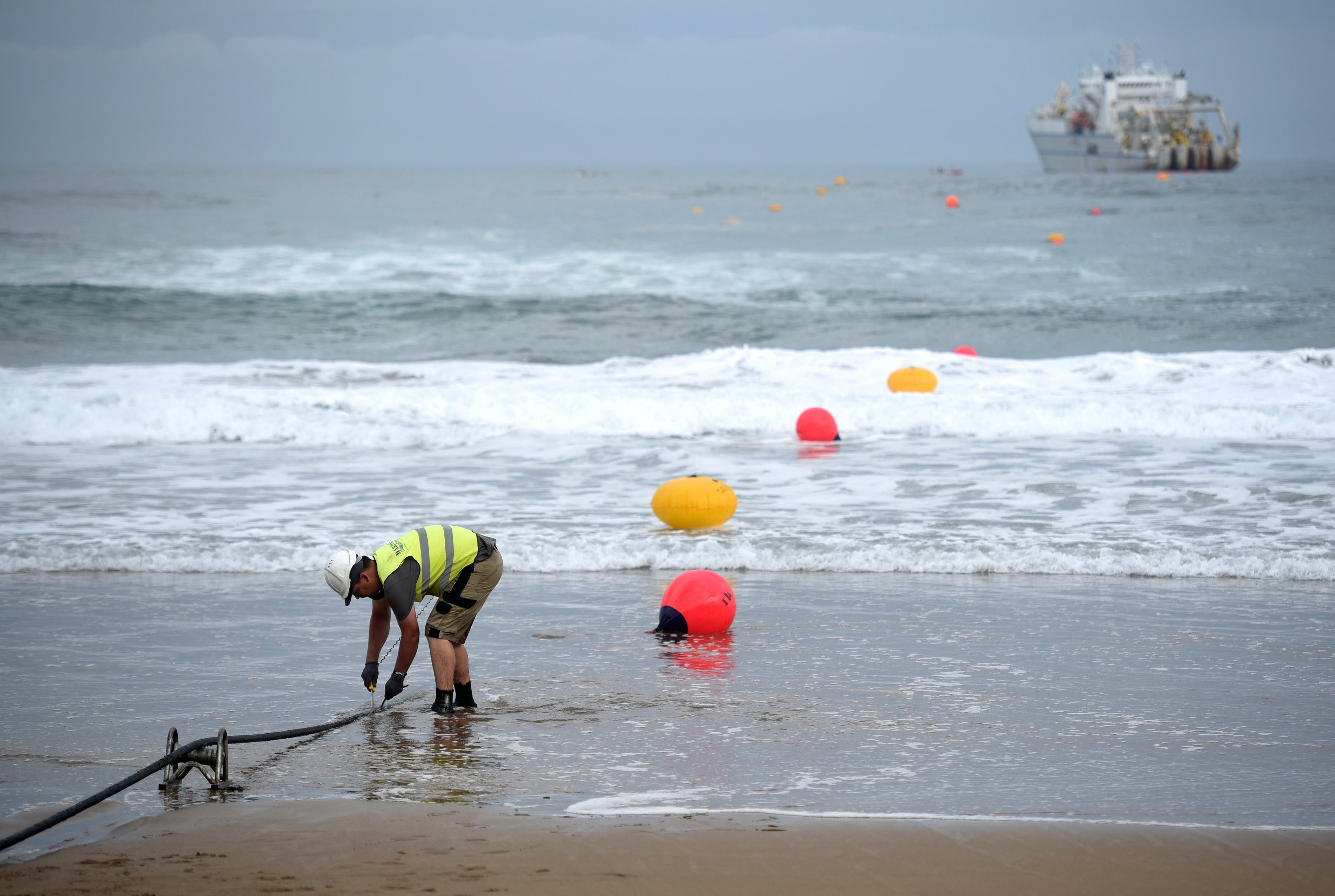 An operator works during the mooring of an undersea fiber optic cable at Arrietara beach near the Spanish Basque village of Sopelana