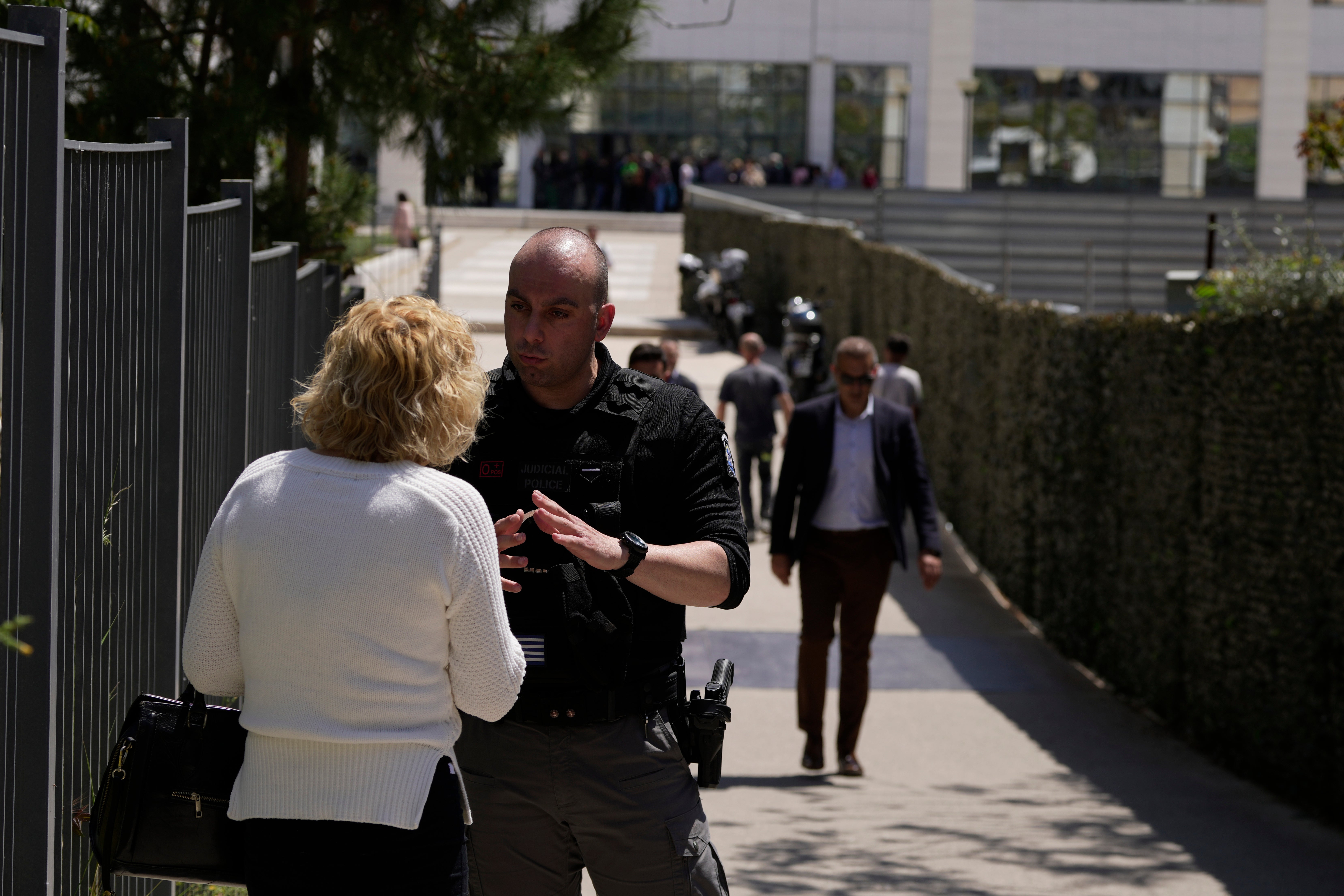 A policeman speaks with a woman outside a courthouse after a gunman opened fire, leaving several people wounded in Athens, on Tuesday, 28 April 2026