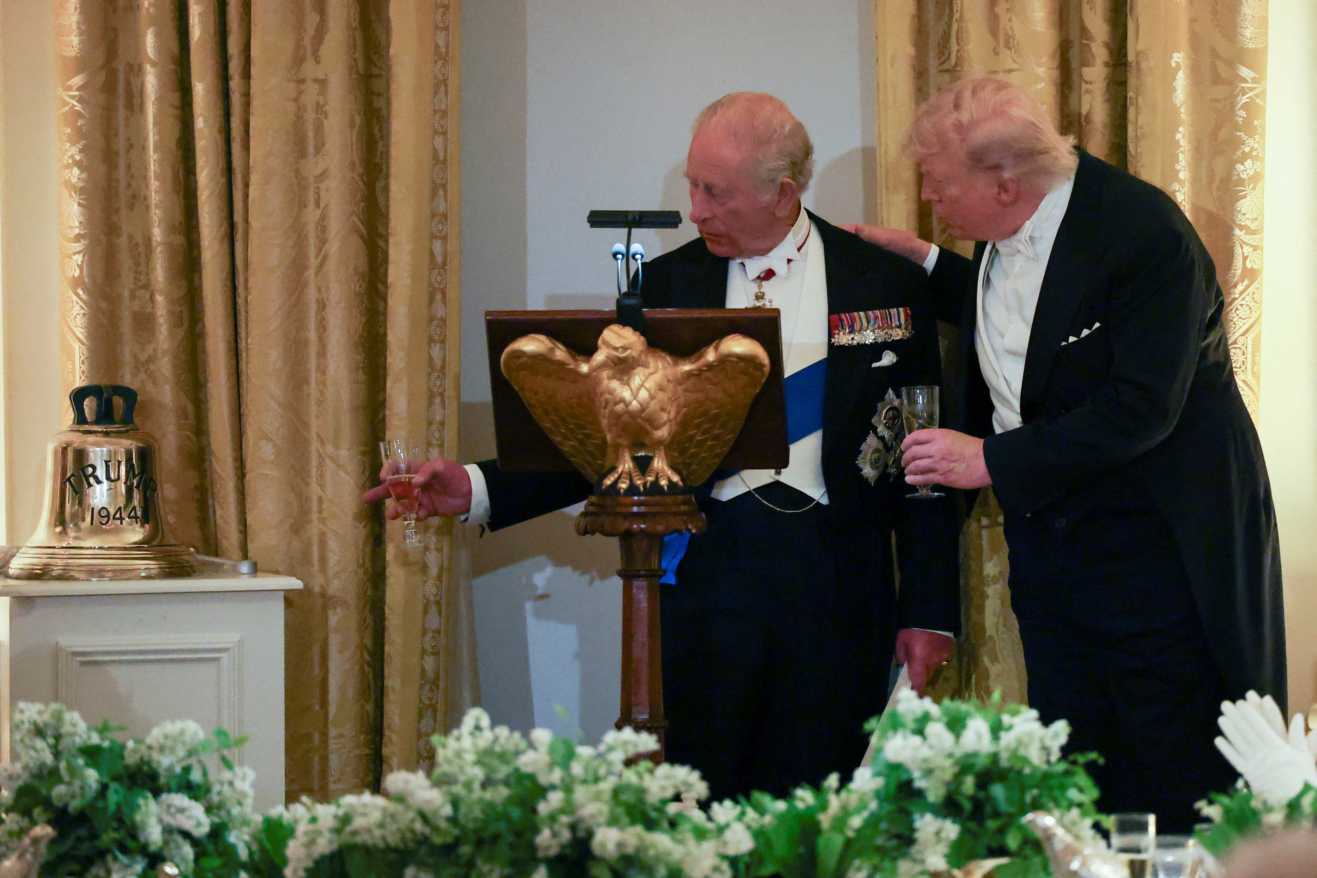 Britain's King Charles points at the bell he presented to U.S. President Donald Trump as a gift during a state dinner at the White House. The bell is from former Royal Navy submarine HMS Trump.